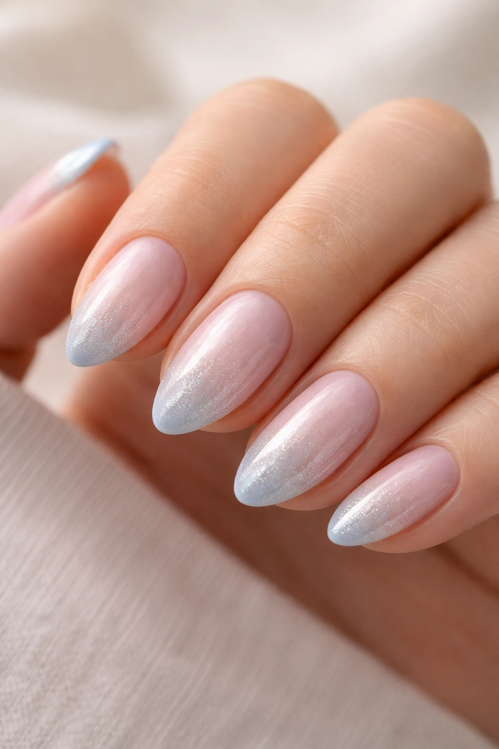 Close-up of a short almond nail with powder blue tip and pearl shimmer