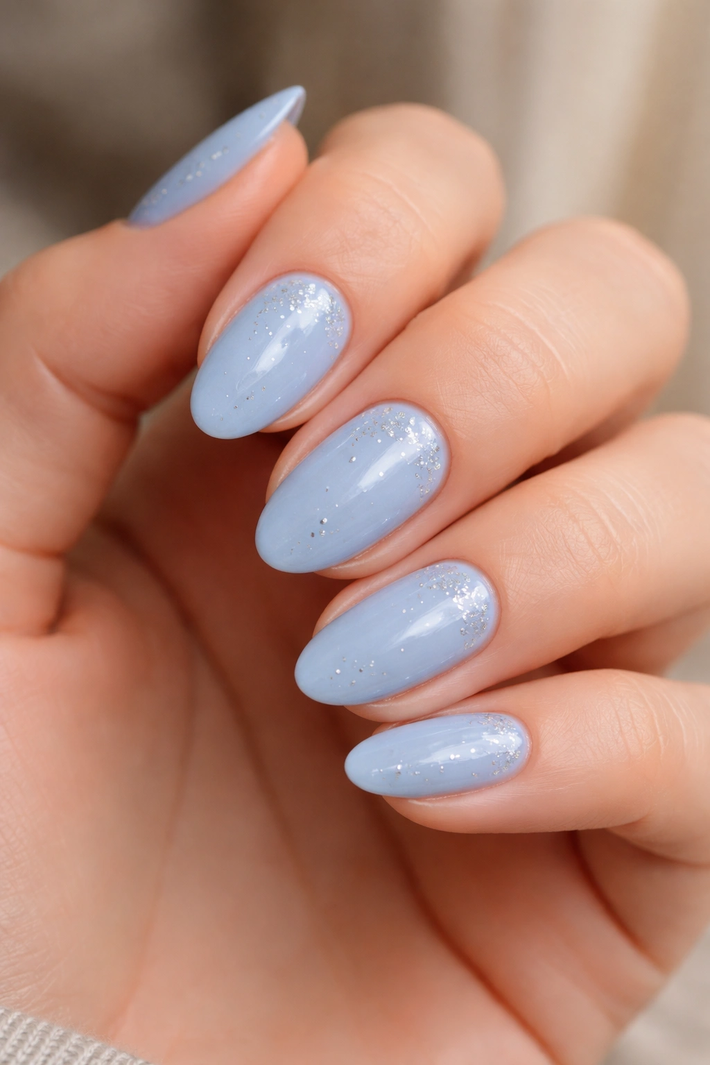 Close-up of short almond nails with powder blue and tiny silver dots