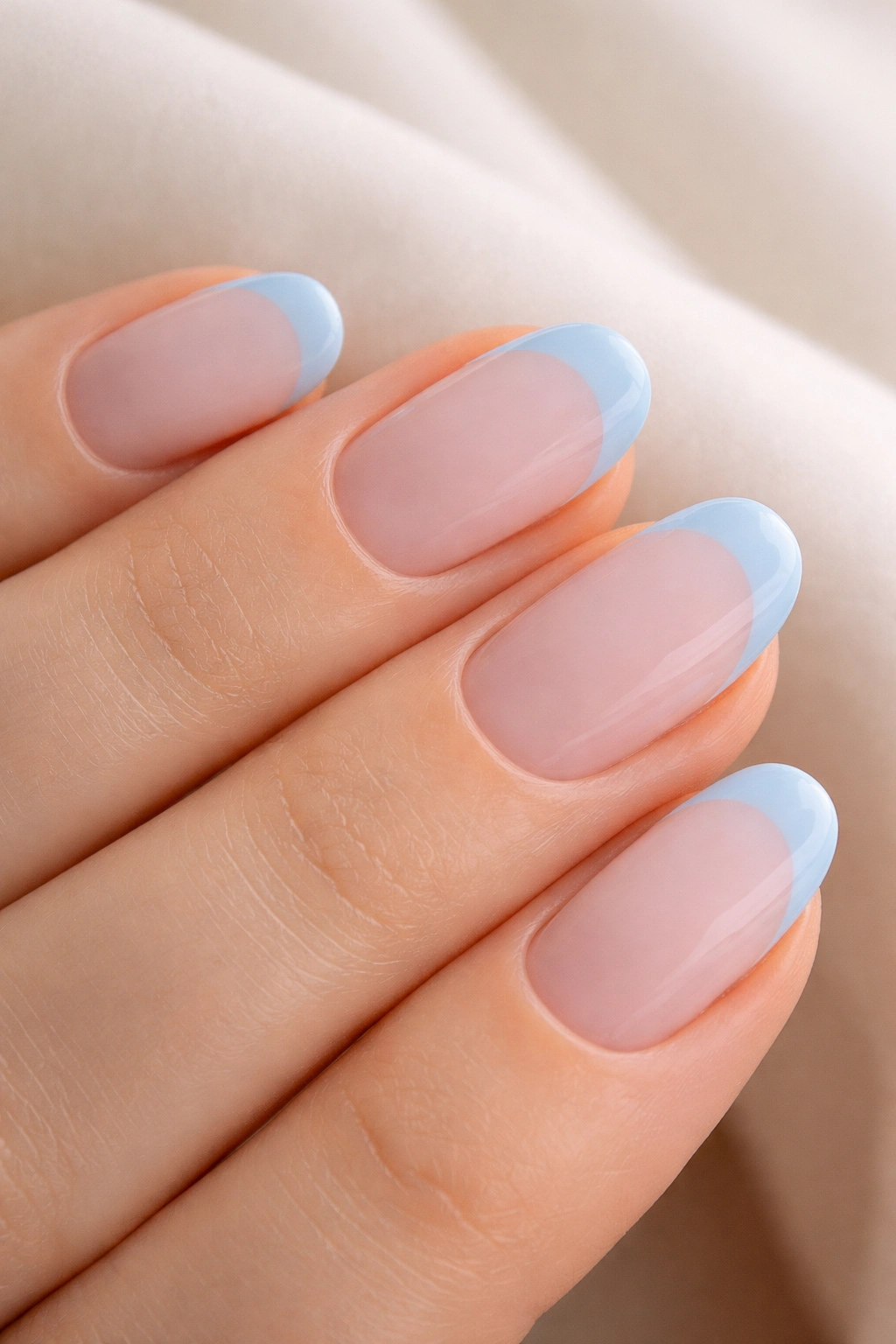 Close-up of short oval nails with powder blue tips on pink base
