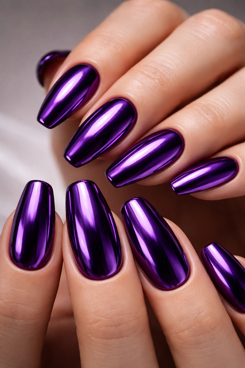 Close-up of royal purple chrome nails with mirror finish in a studio setting