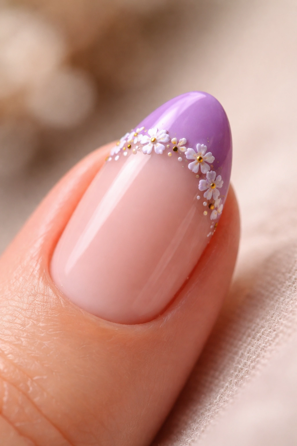 Close-up of a short almond nail with purple French tip and micro floral art along the tip line