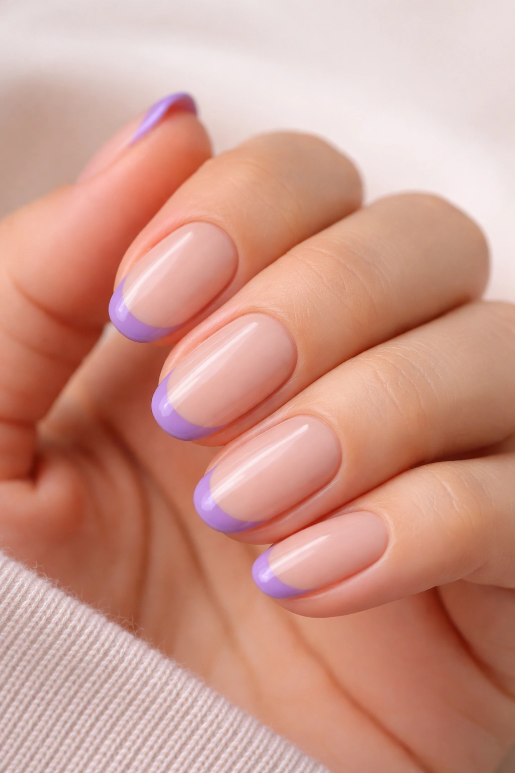 Close-up of purple French tips on a nude base on short oval nails