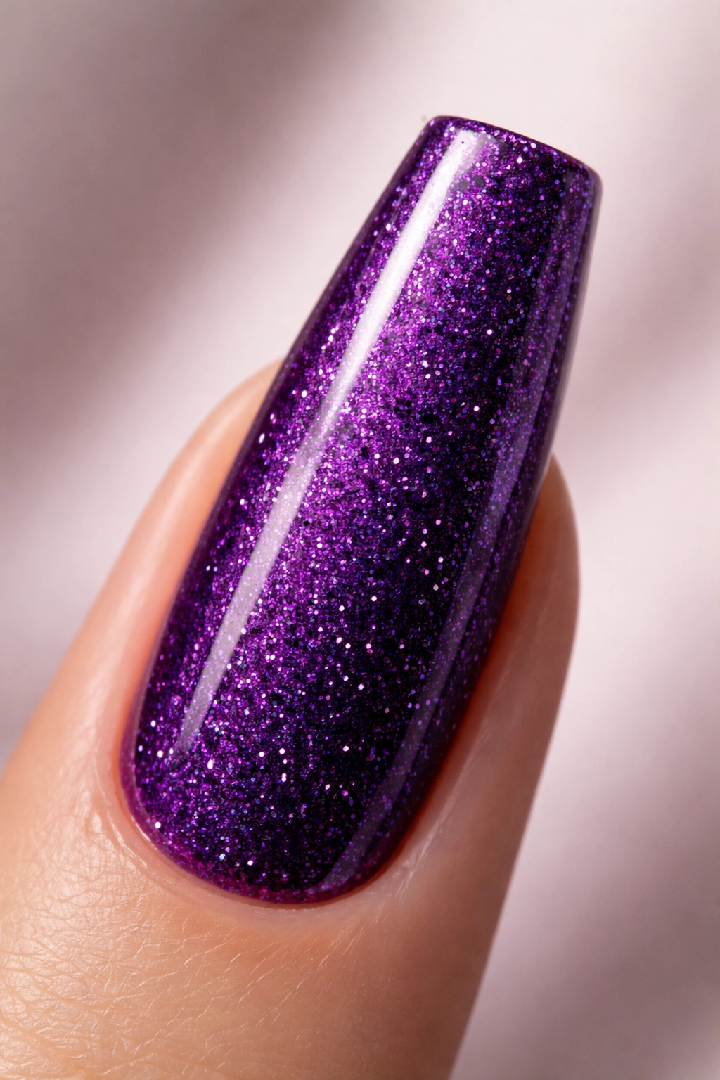 Close-up of a deep amethyst purple glitter coffin nail on a neutral background.