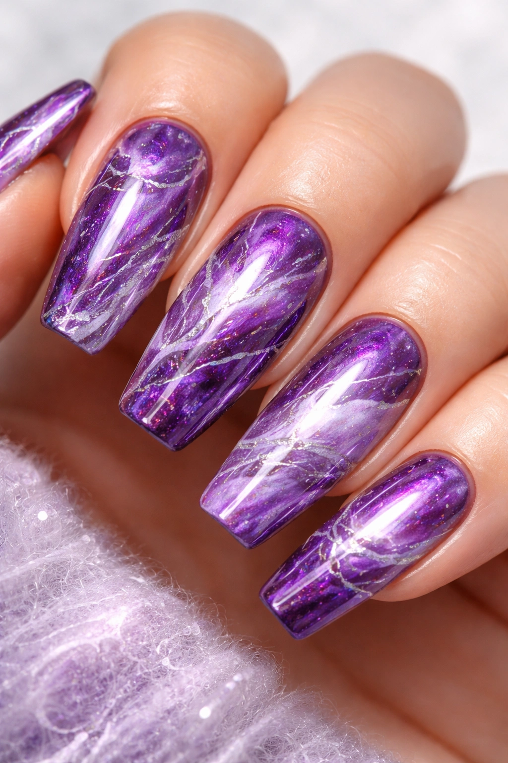 Close-up of purple chrome marble nails featuring lavender and violet swirls on a glossy chrome finish