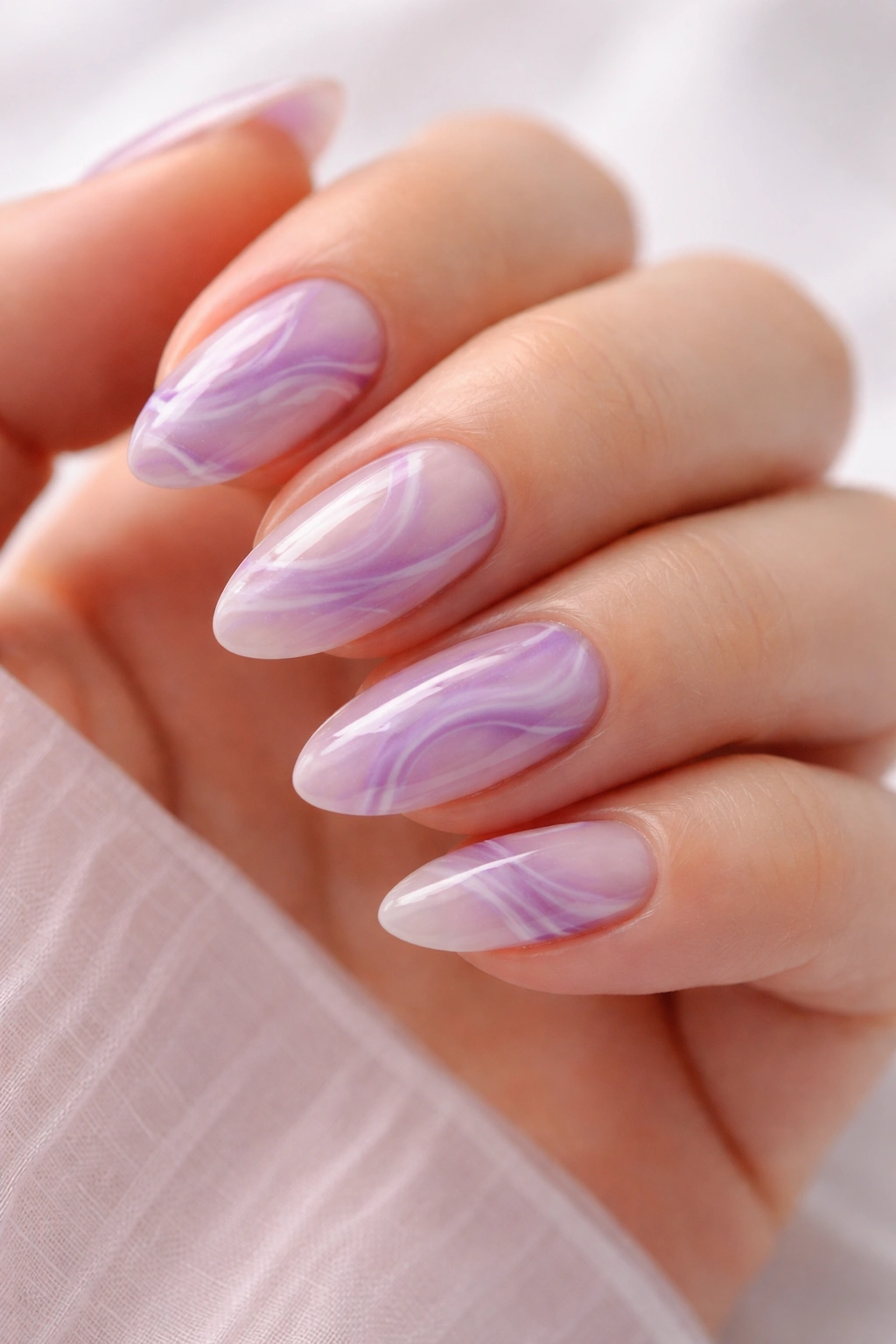 Close-up of short almond nails with purple marble swirls and negative space