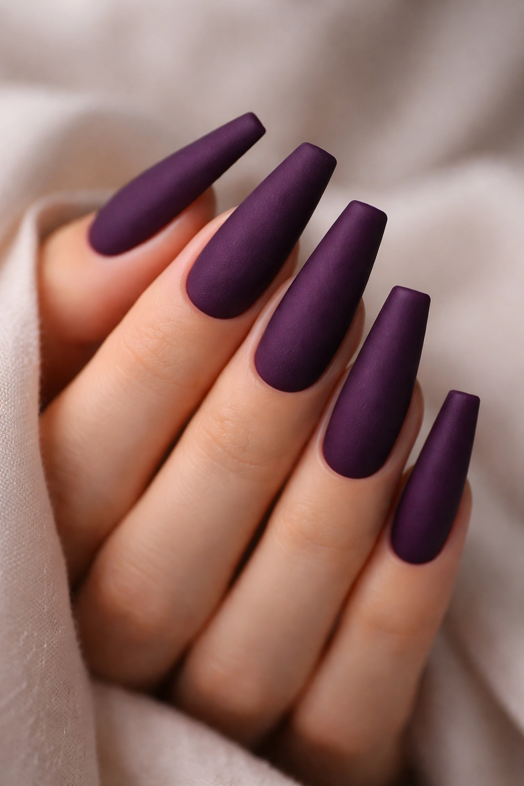 Close-up of coffin nails with deep purple velvet matte finish