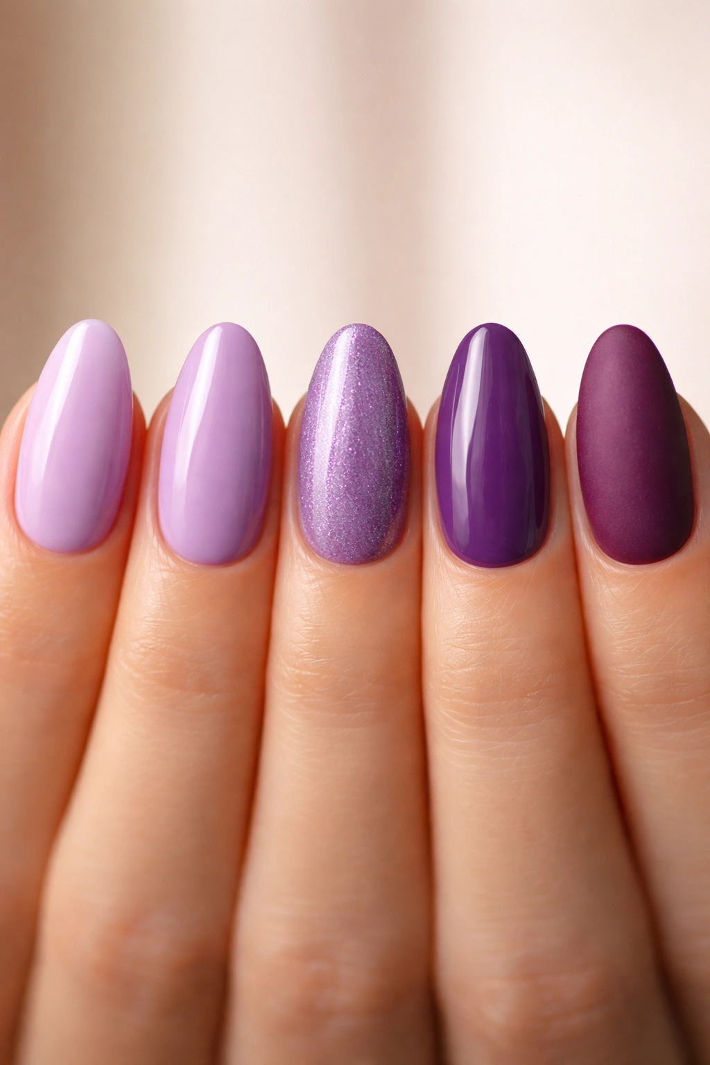 Five short almond nail tips in purple shades from lilac to velvet, showing glossy and matte finishes