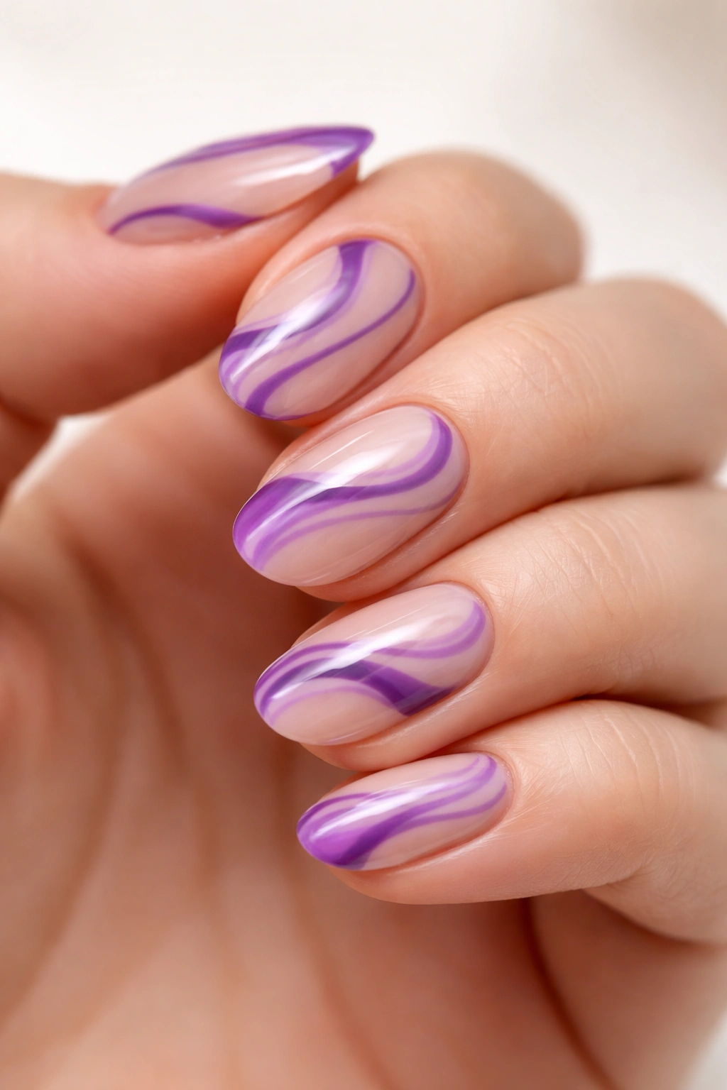 Short oval nail with purple swirls and nude negative space design