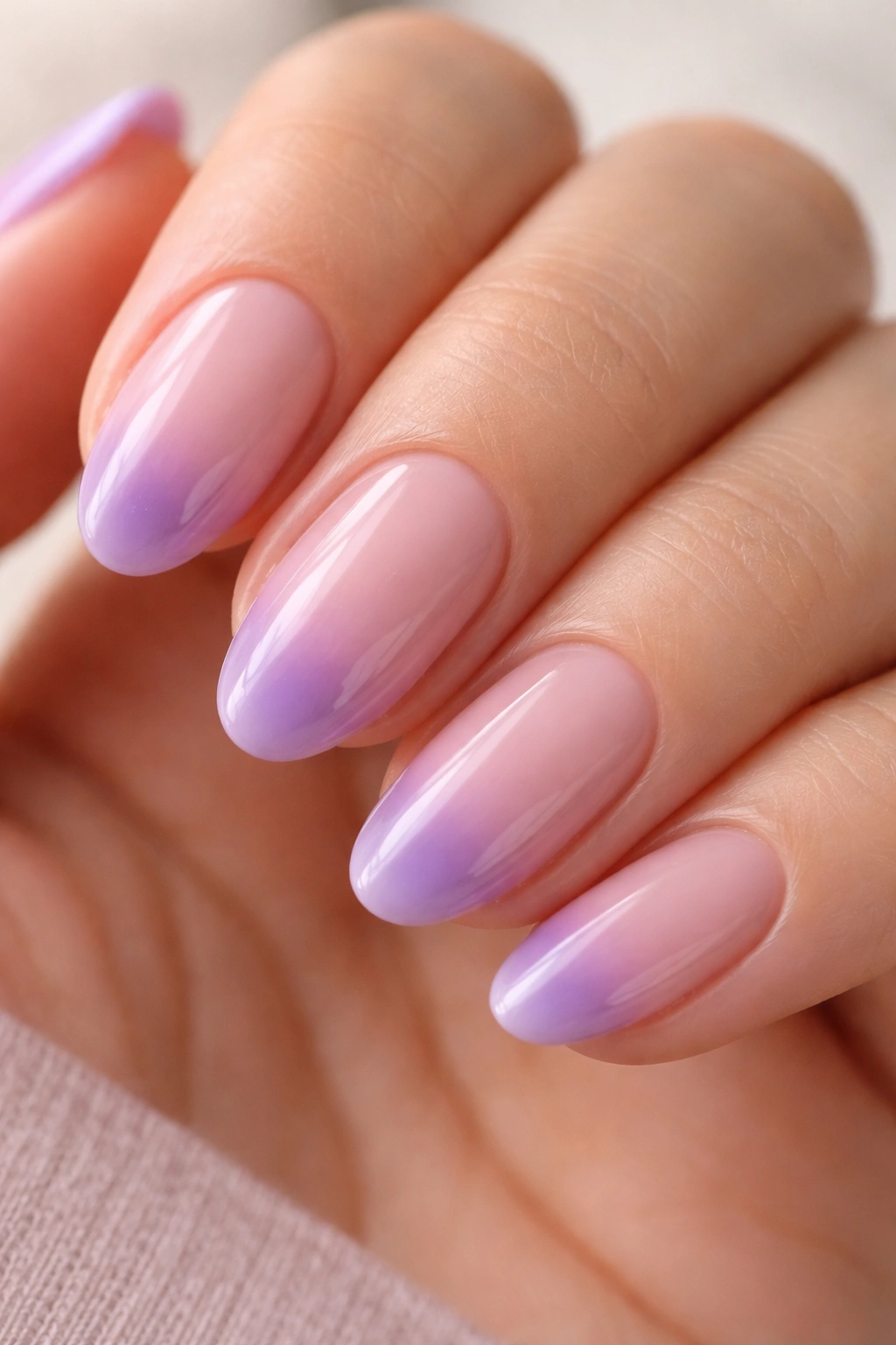 Close-up of a short almond nail with purple gradient fading to a sheer base