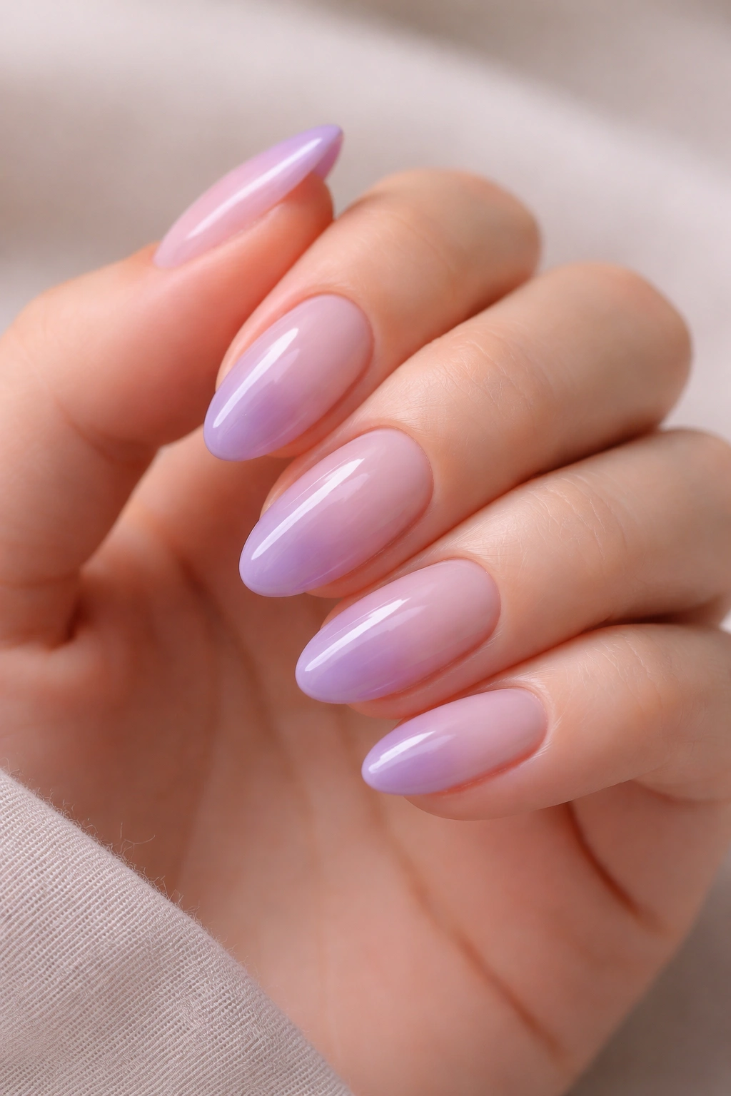 Close-up of short almond nails with nude to purple ombre and glossy finish
