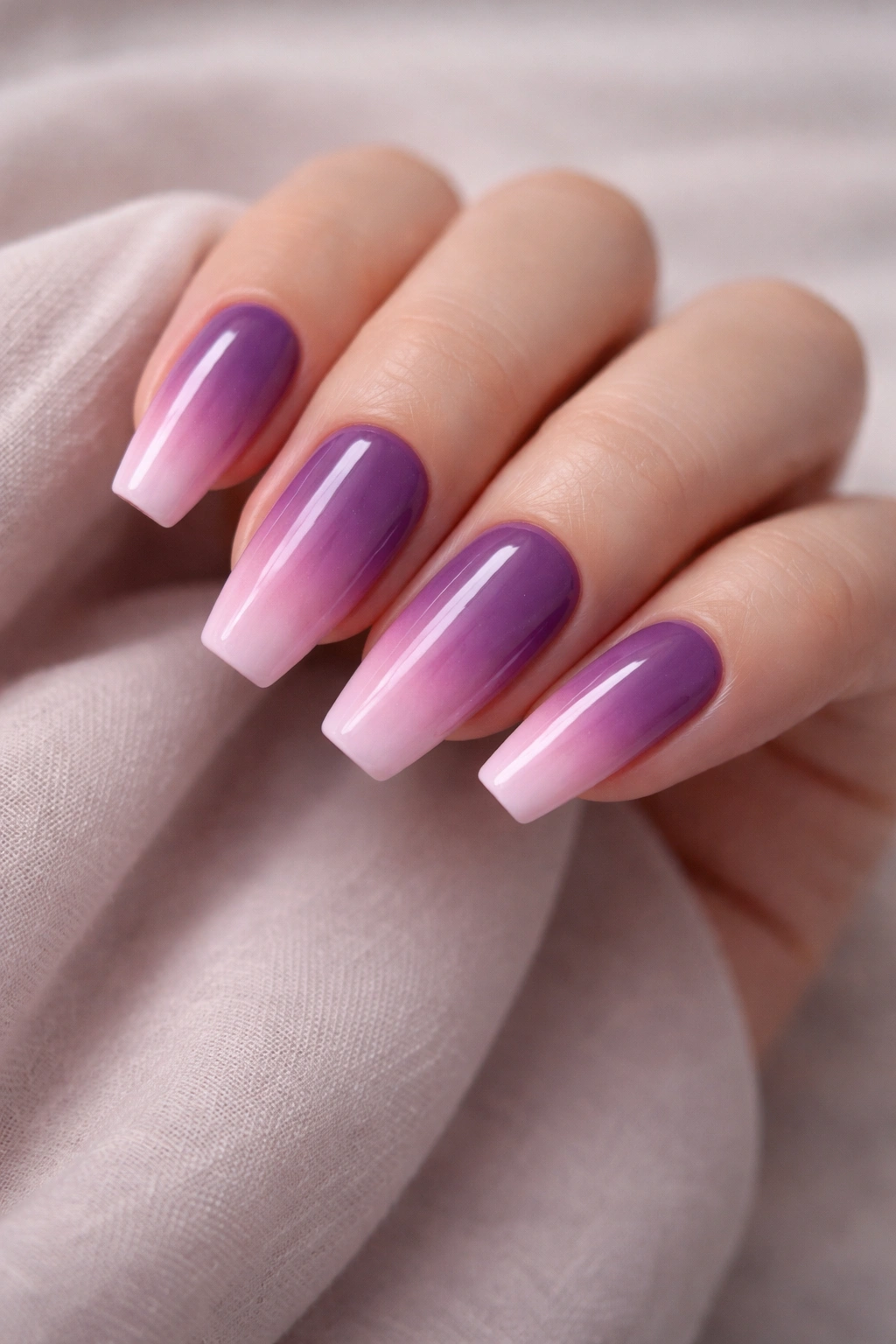 Close-up of medium-length purple-to-pink ombre nails
