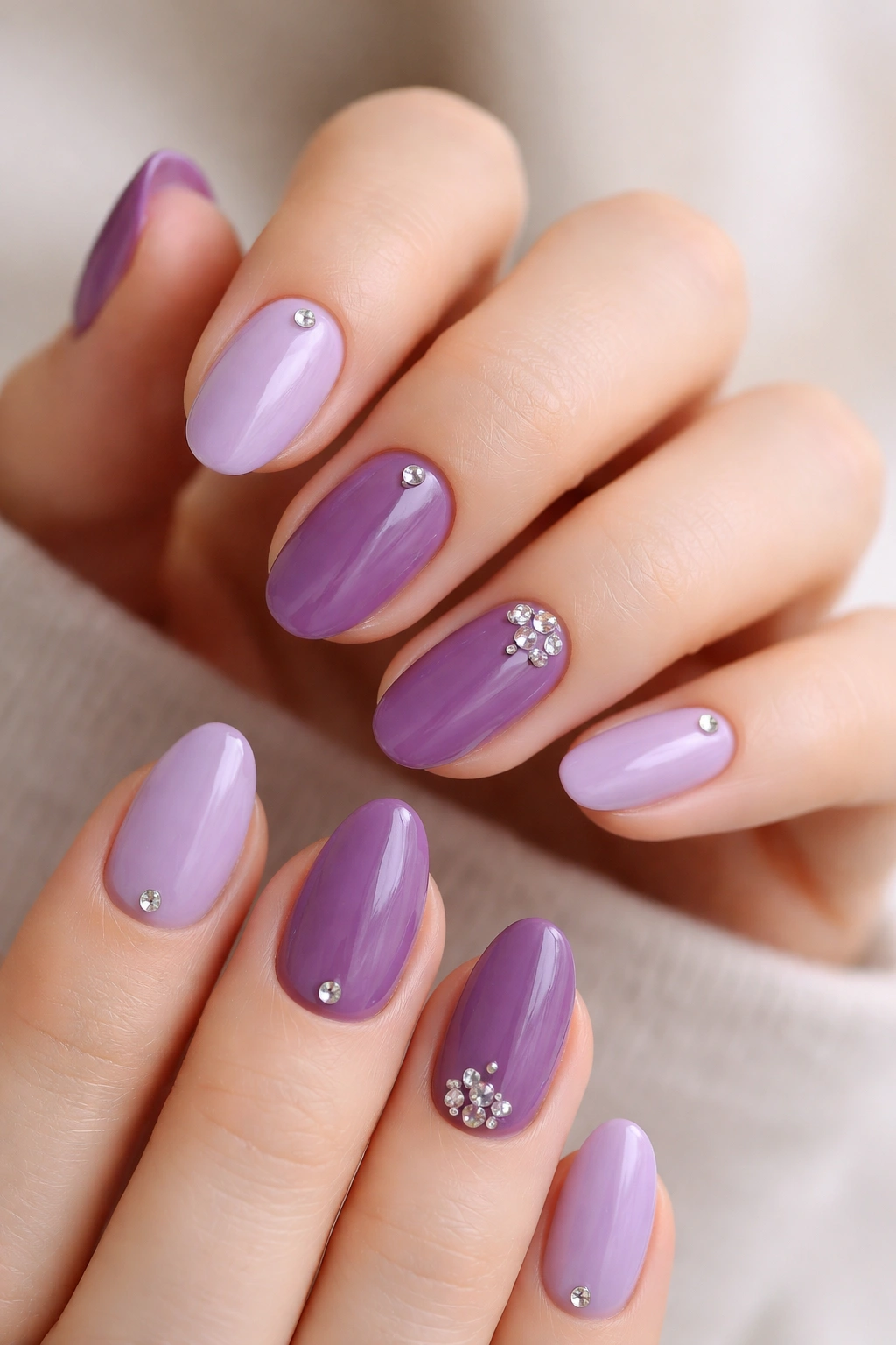 Purple nails with tiny rhinestones on short almond nails near the cuticle