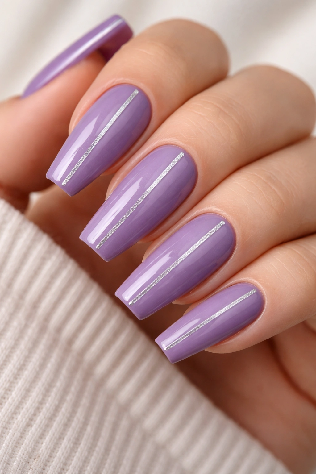 Close-up of purple coffin nails with thin silver stripes