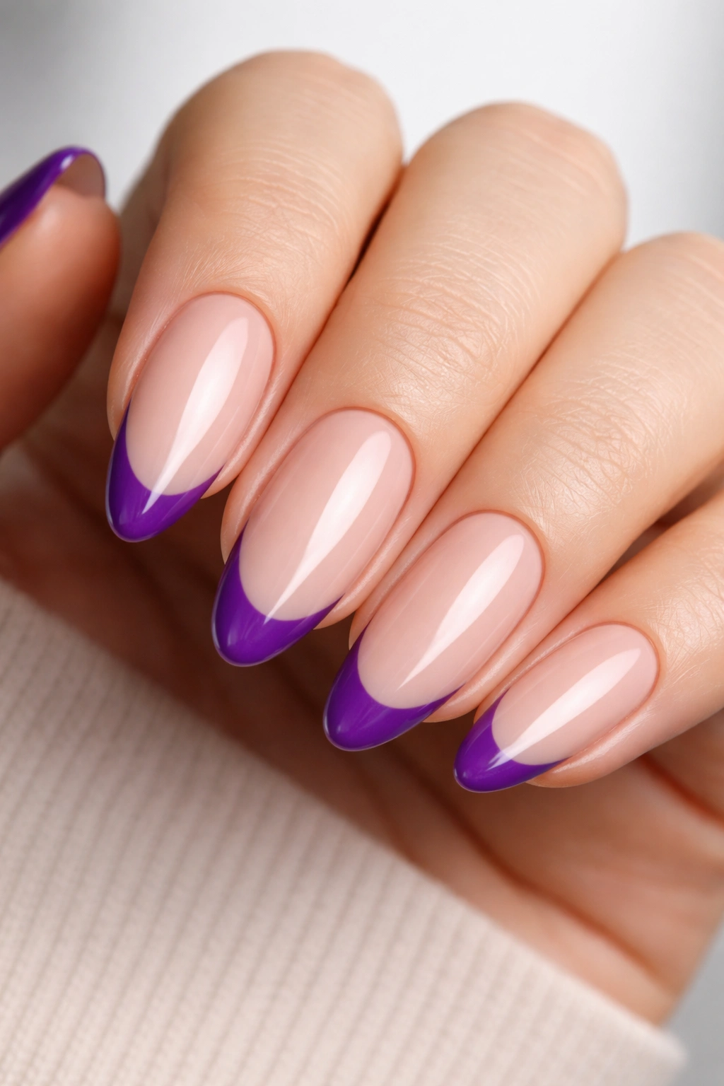 Nude almond nails with crisp purple tips on the edge