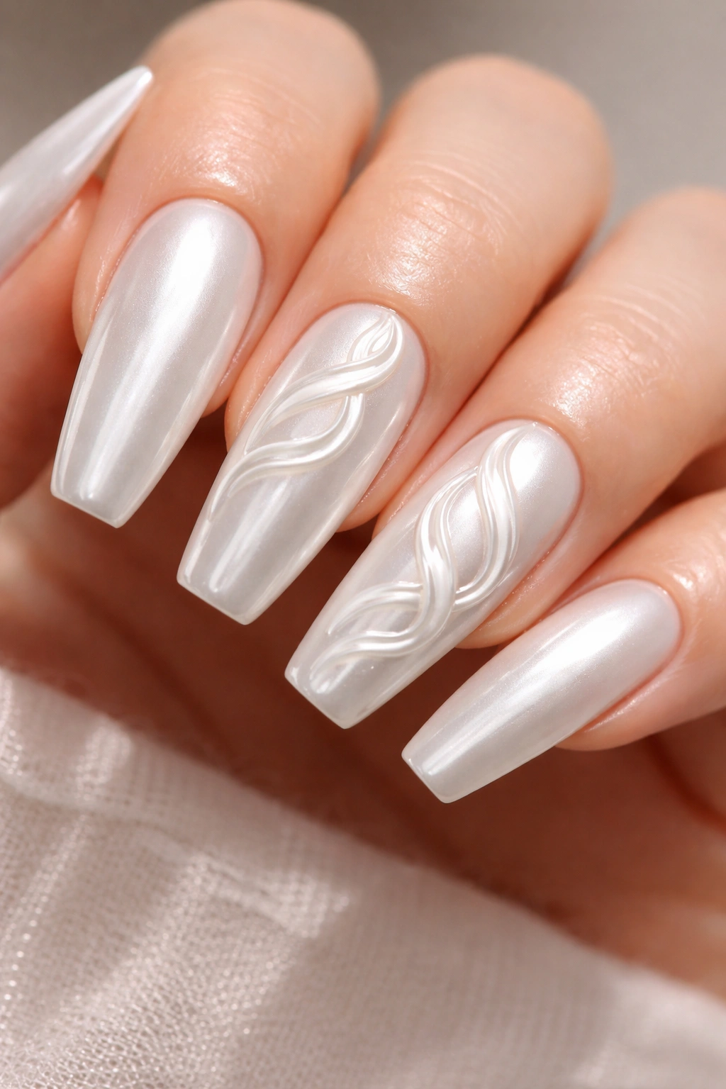 Close-up of glazed white chrome nails with raised 3D ribbon swirls