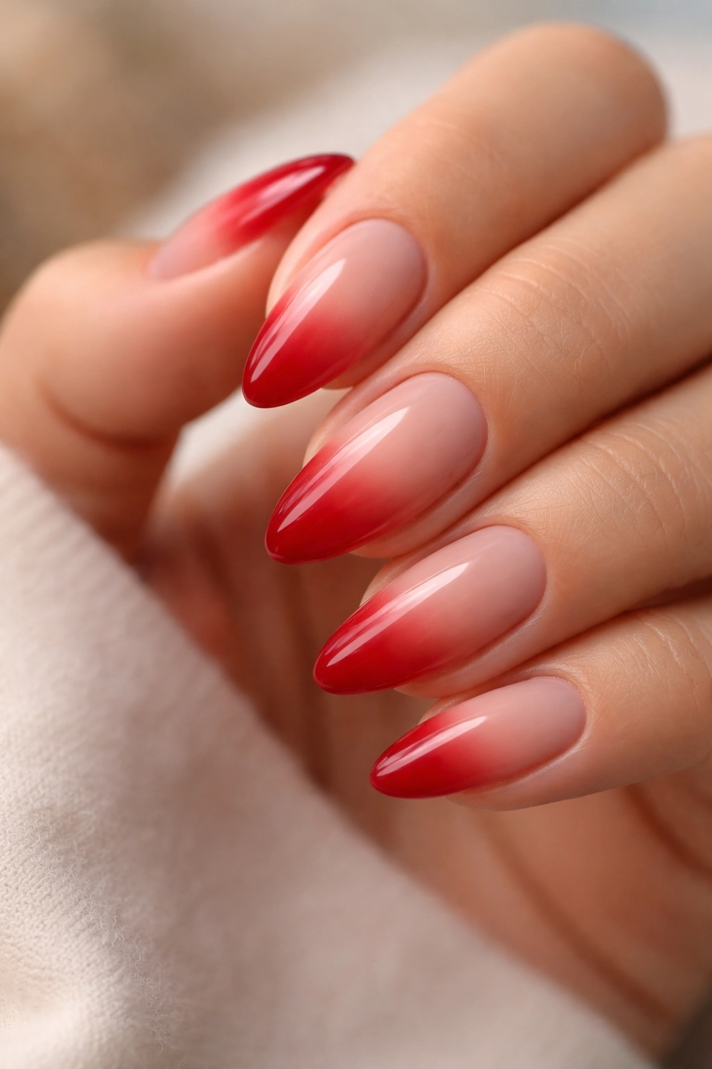 Close-up of almond nails with red-to-nude ombre and blurred smile line