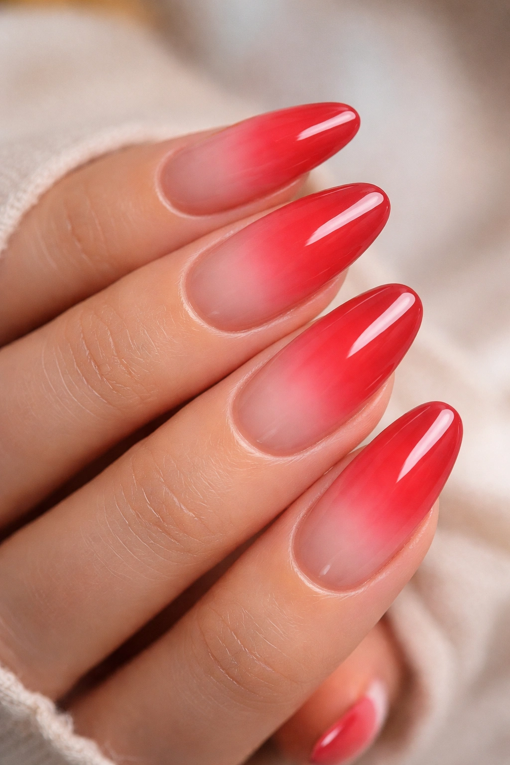 Long oval nails with red aura gradient fading to nude