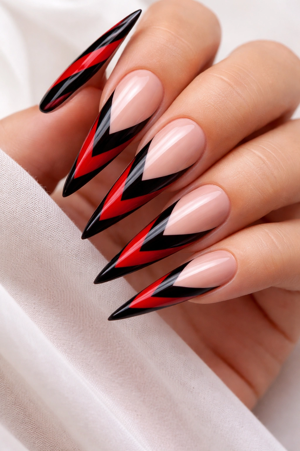 Stiletto nails with red and black chevron pattern.