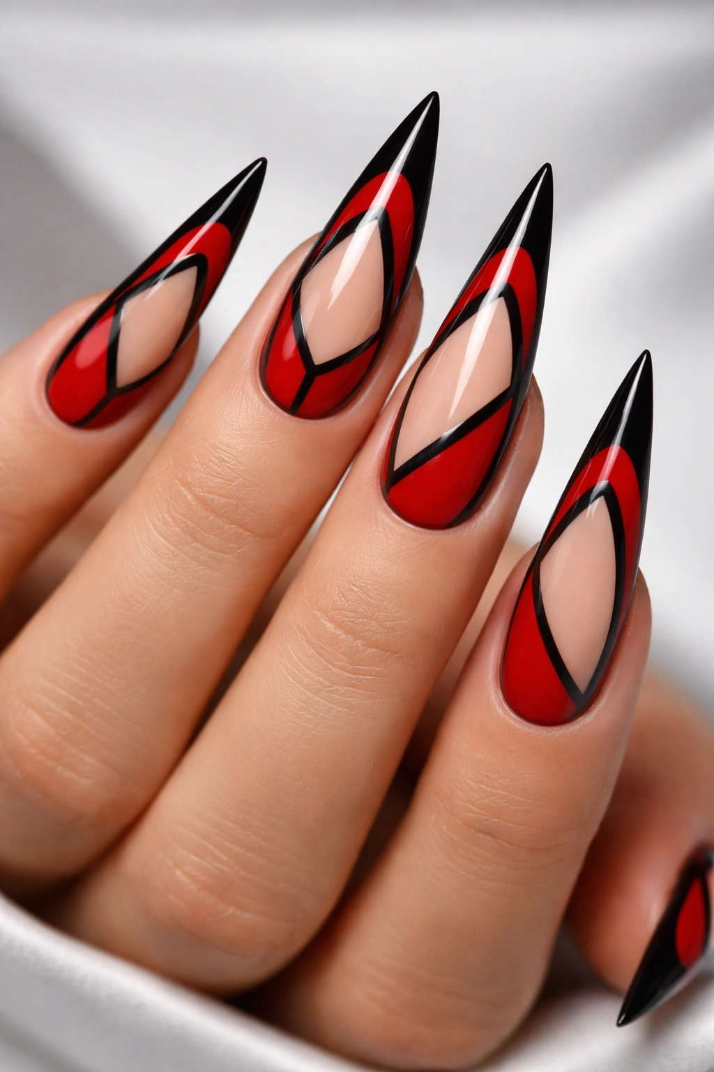 Red nails with black negative space design on stiletto shape.