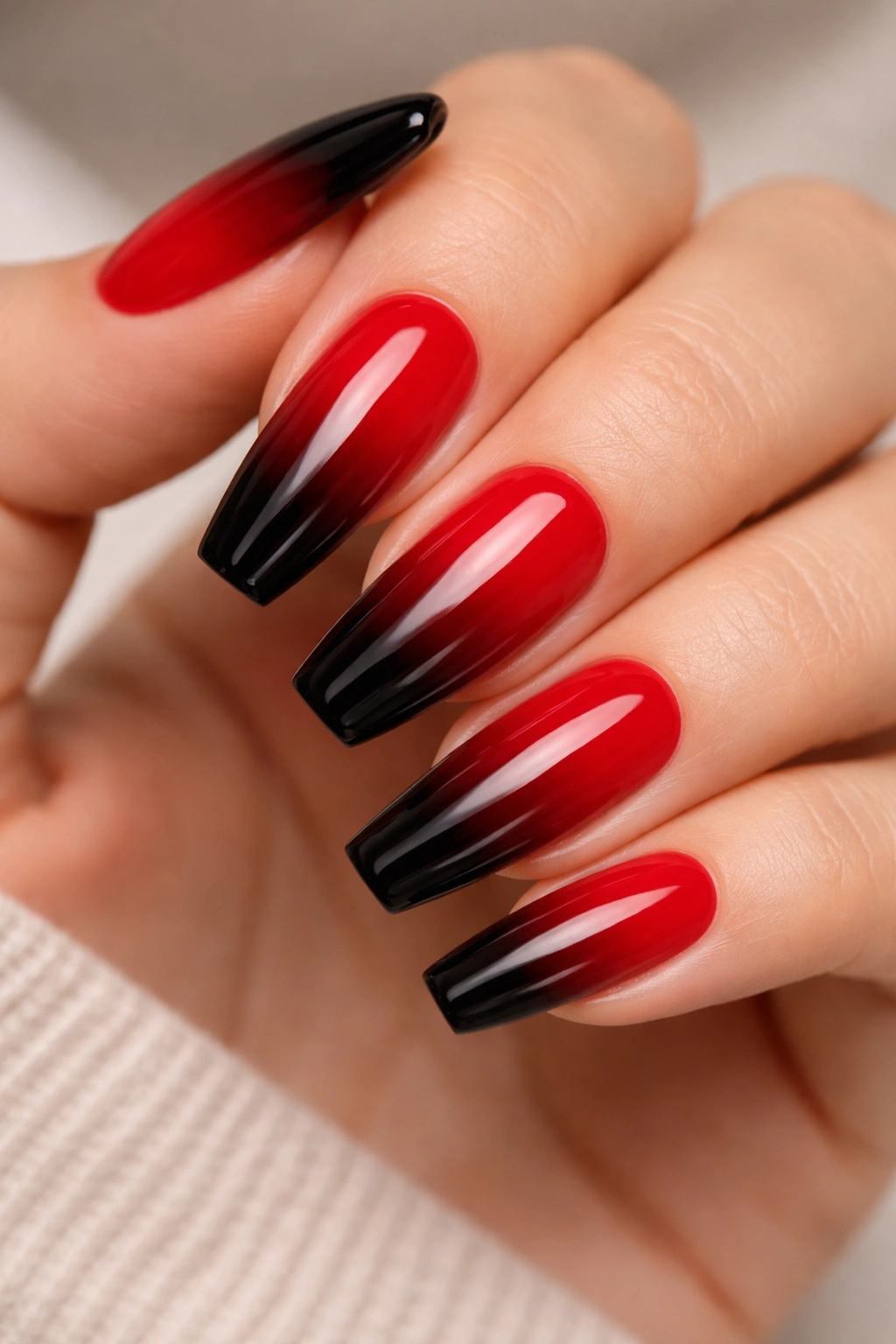 Close-up of medium coffin nails with a red-to-black ombre gradient on a neutral background