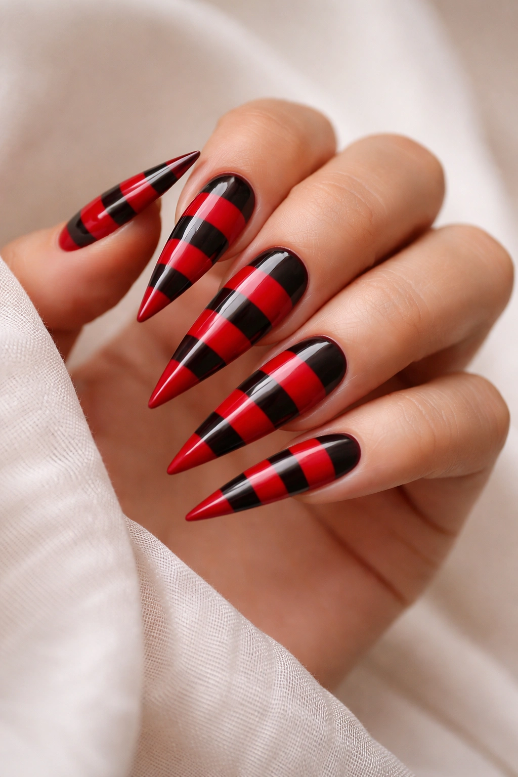 Nails with red and black horizontal stripes on stiletto shape.