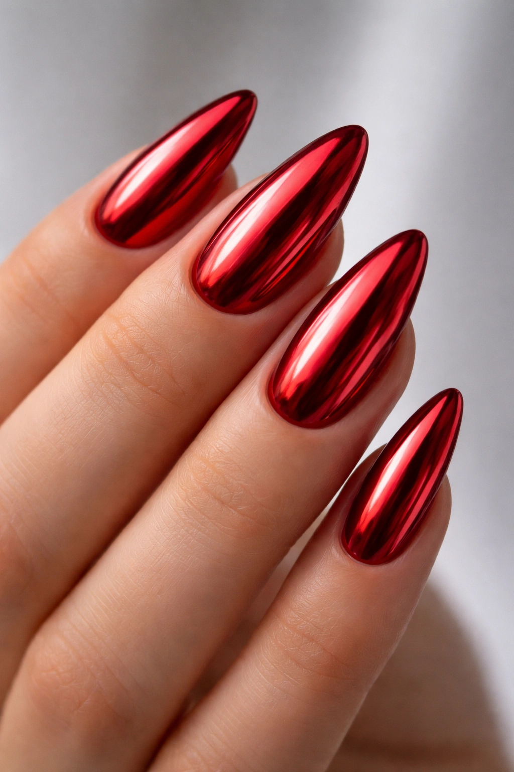 Close-up of almond-shaped nails with chrome red metallic finish