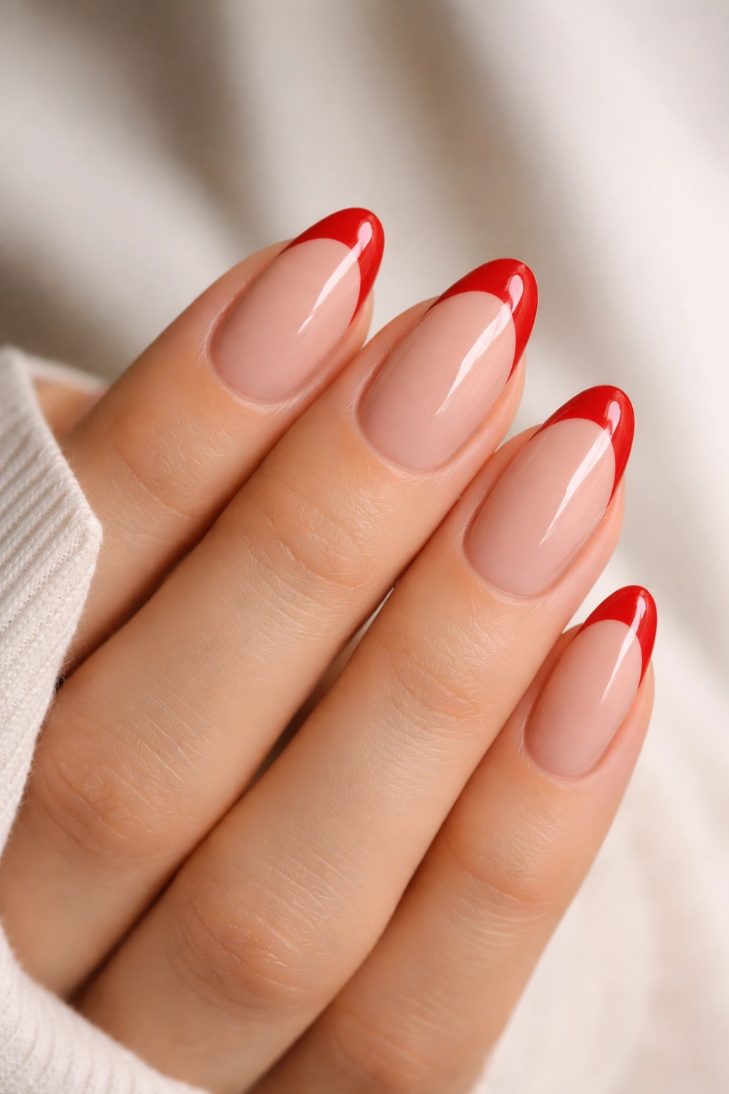 Nude-based almond nails with cherry red French tips