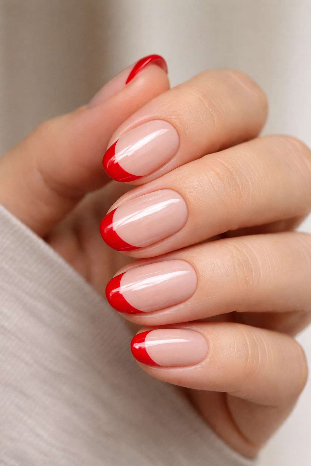 Close-up of short oval nails with red French tips on nude base