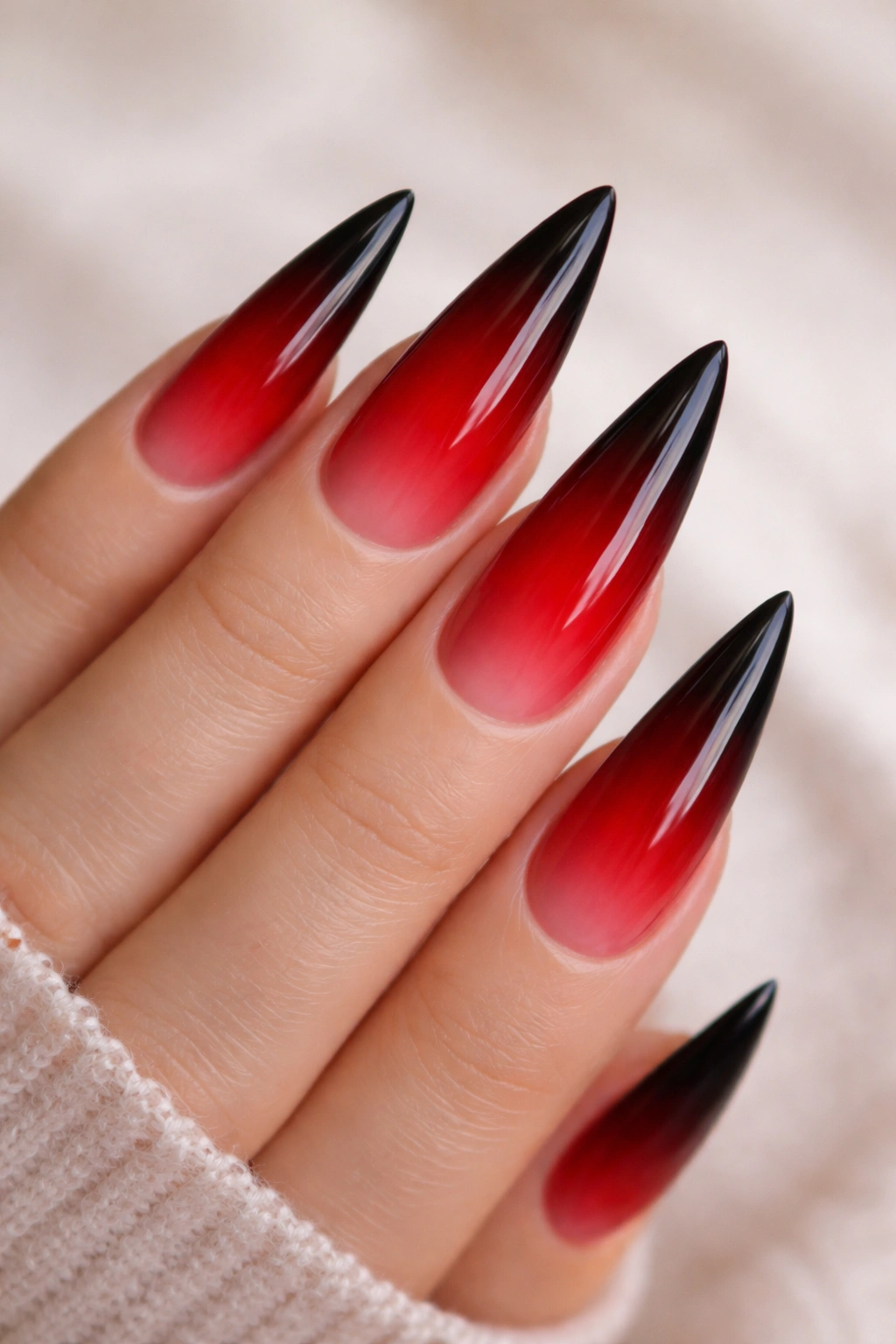 Close-up of red to black ombré stiletto nails.