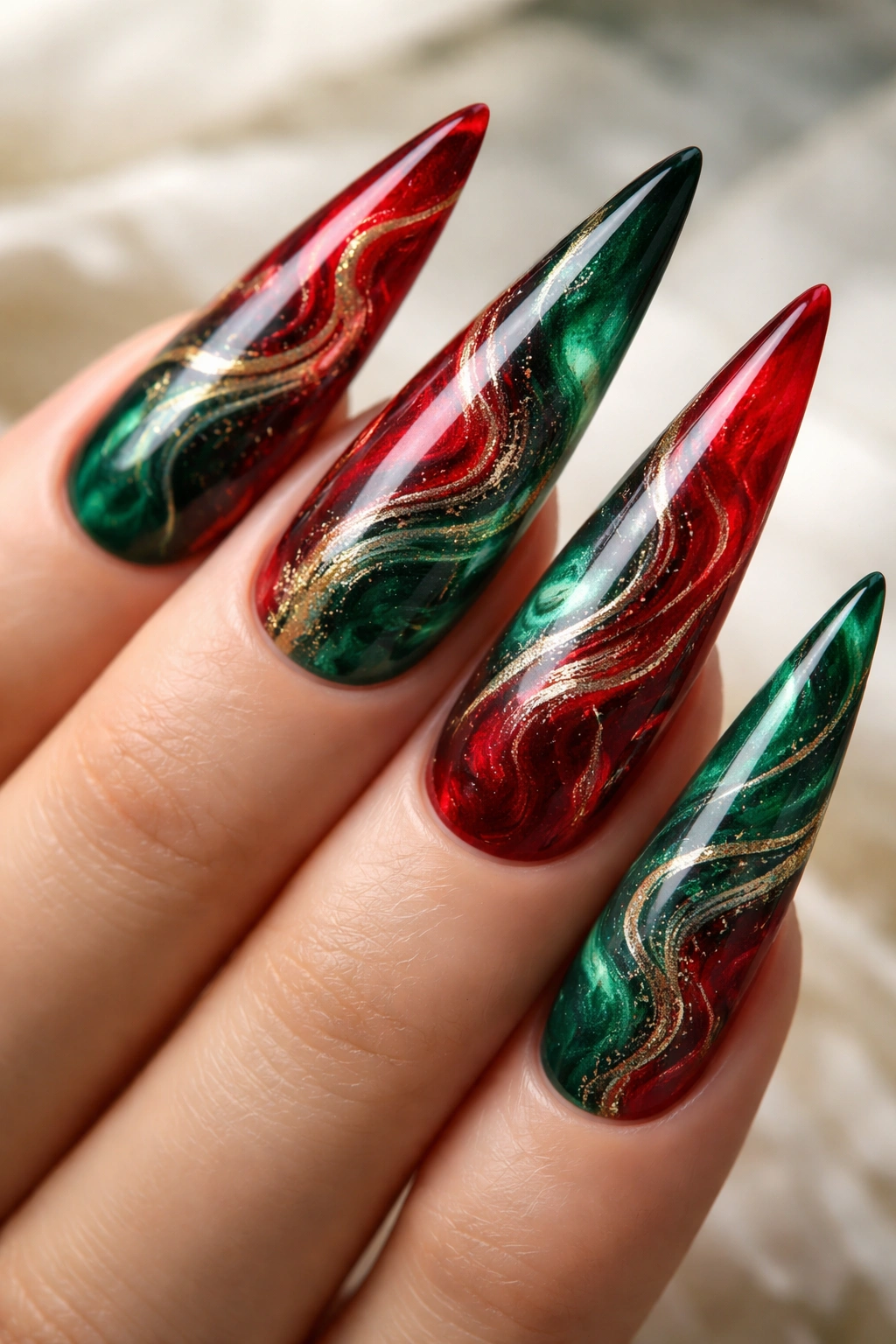 Close-up of red and green marble-styled stiletto nails