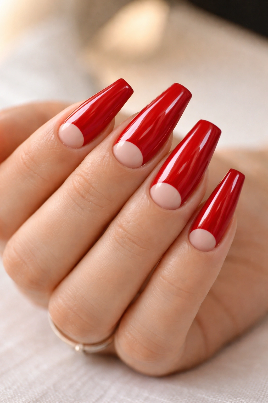 Red nails with a half-moon negative space near the cuticle on ballerina-shaped nails.