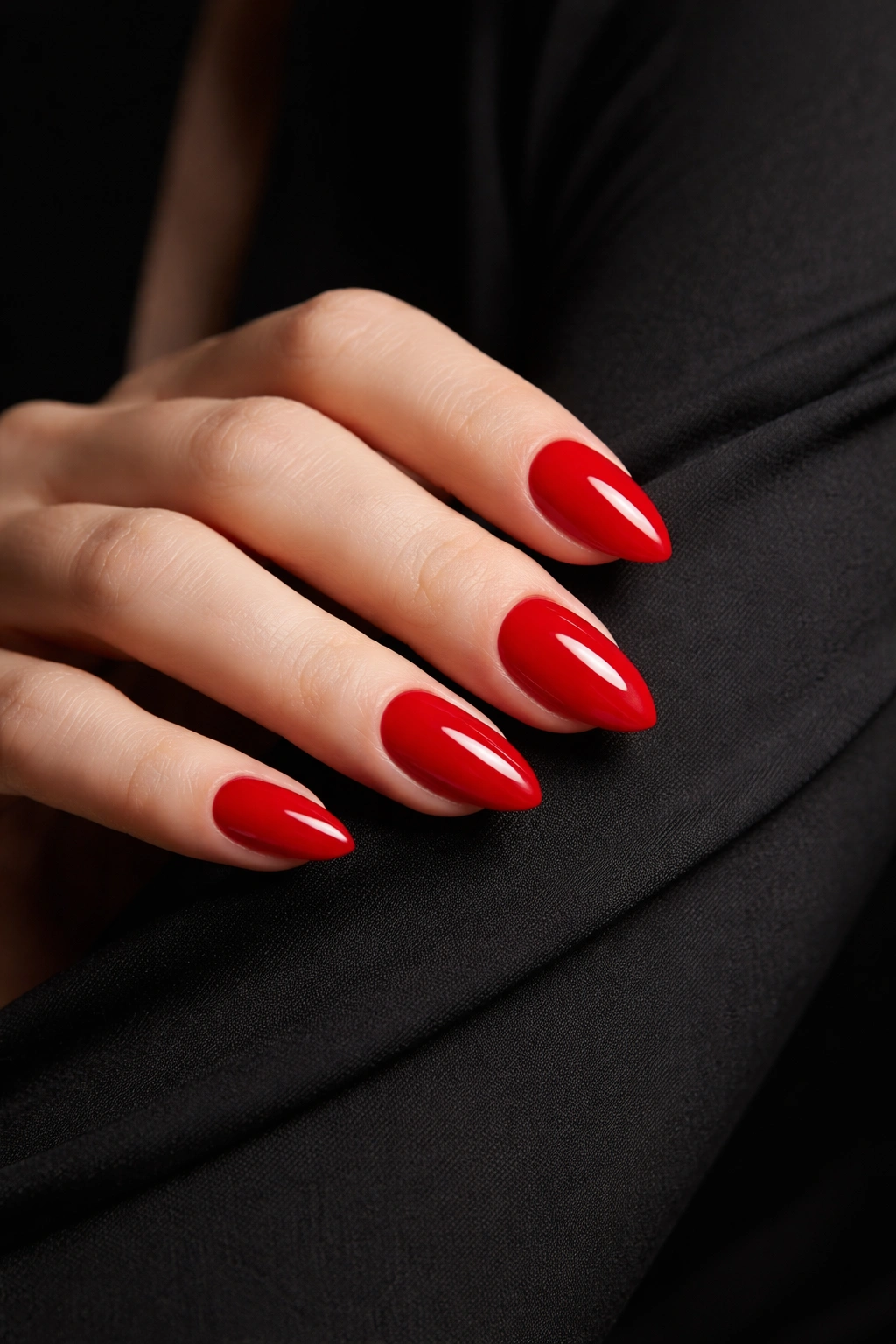 Close-up of glossy red nails against a black dress sleeve
