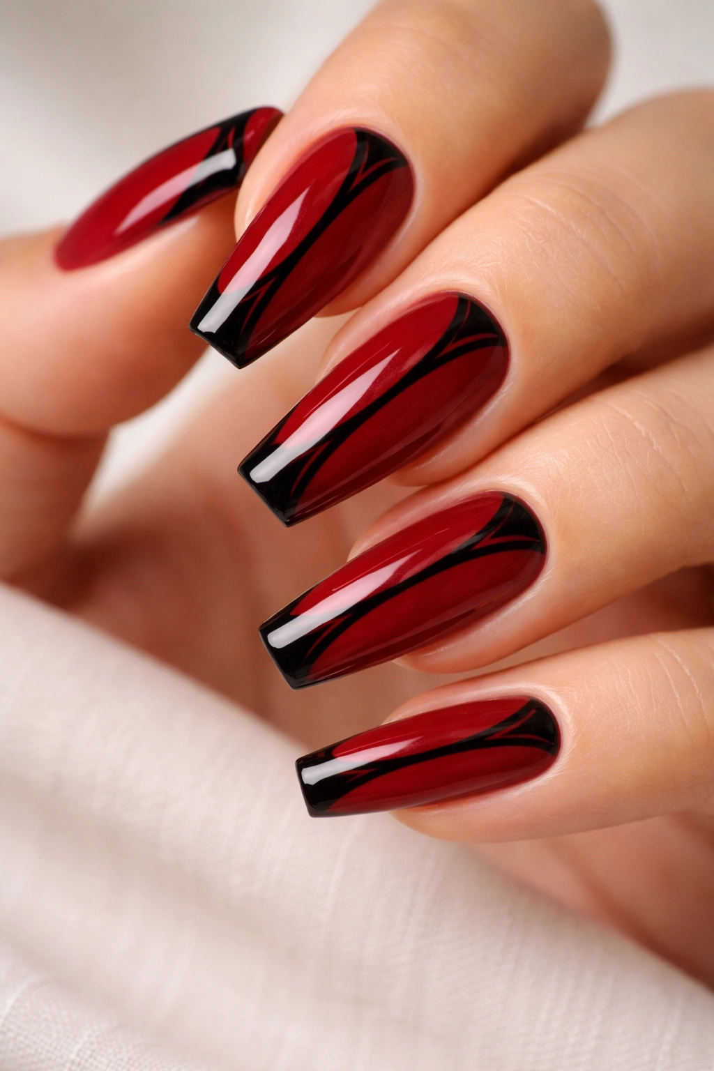Close-up of medium coffin nails with glossy red base and black cat-eye center line