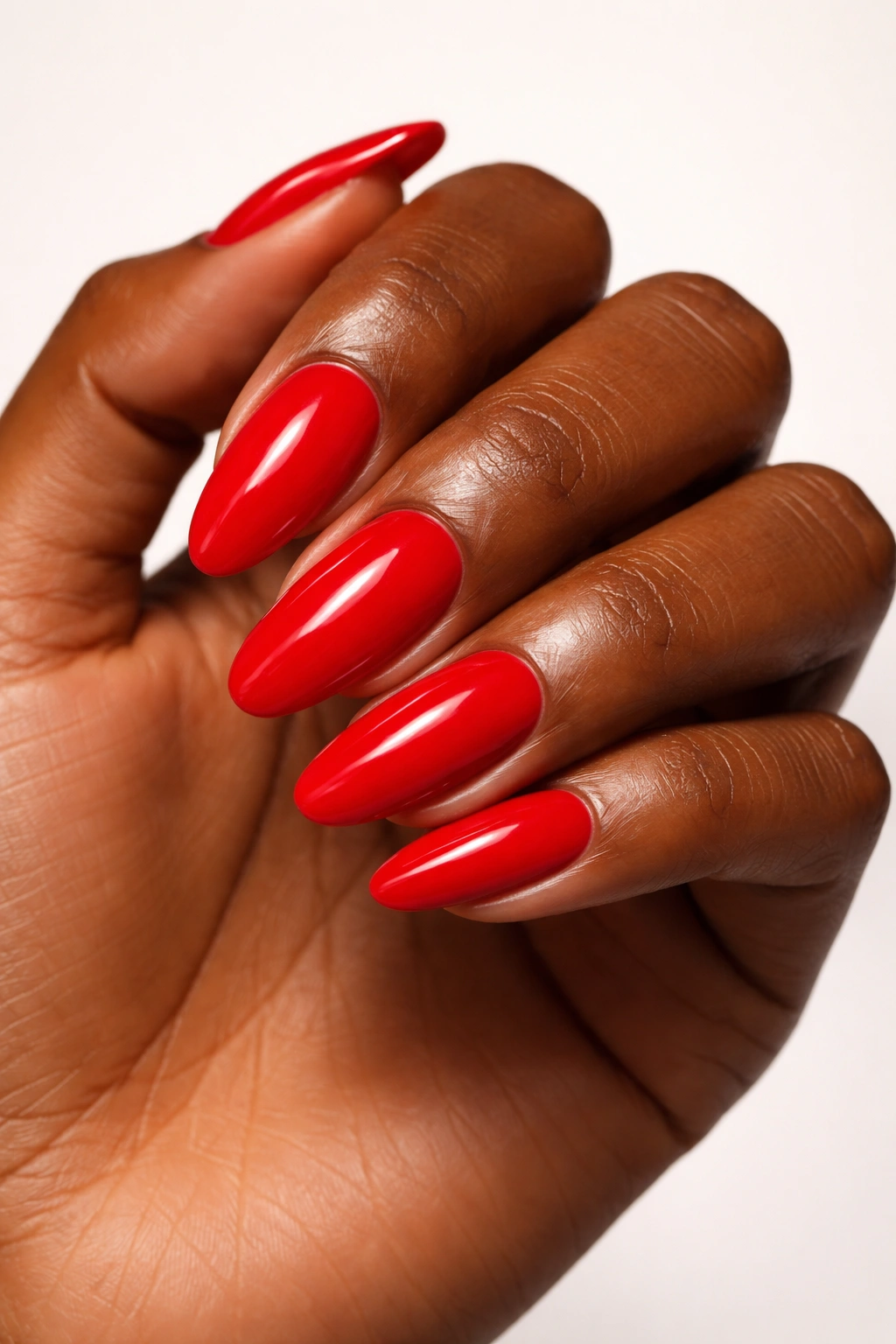Bright red nails on dark skin against neutral backdrop