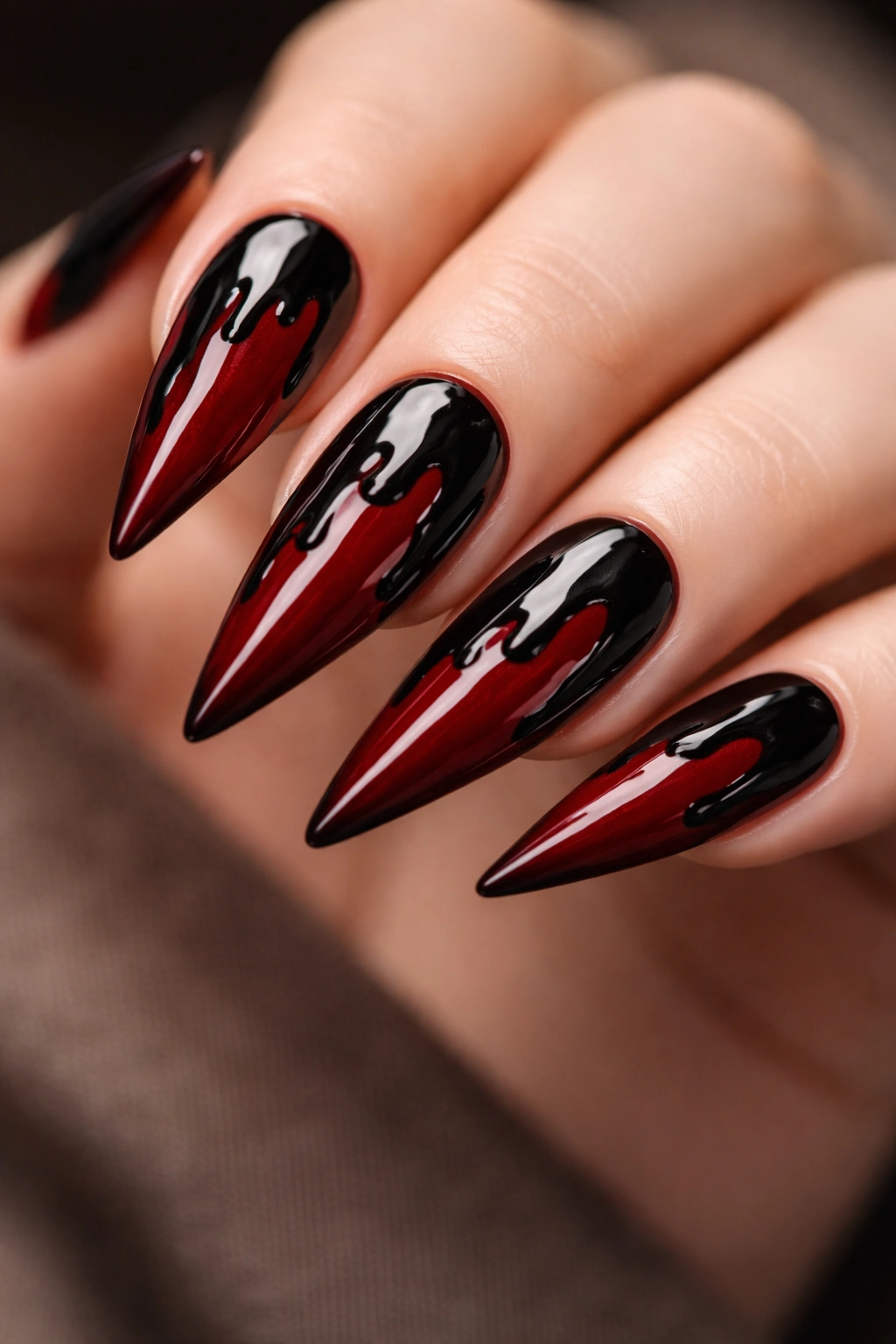 Close-up of blood-red stiletto nails with dripping black patterns from tips toward the cuticles.