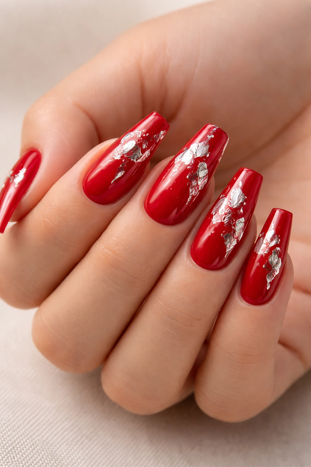 Close-up of red coffin nails with silver foil accents catching light