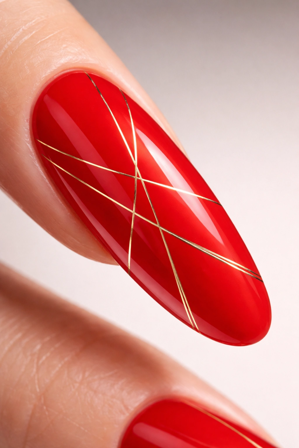 Close-up of a red round acrylic nail with metallic geometric lines under studio light