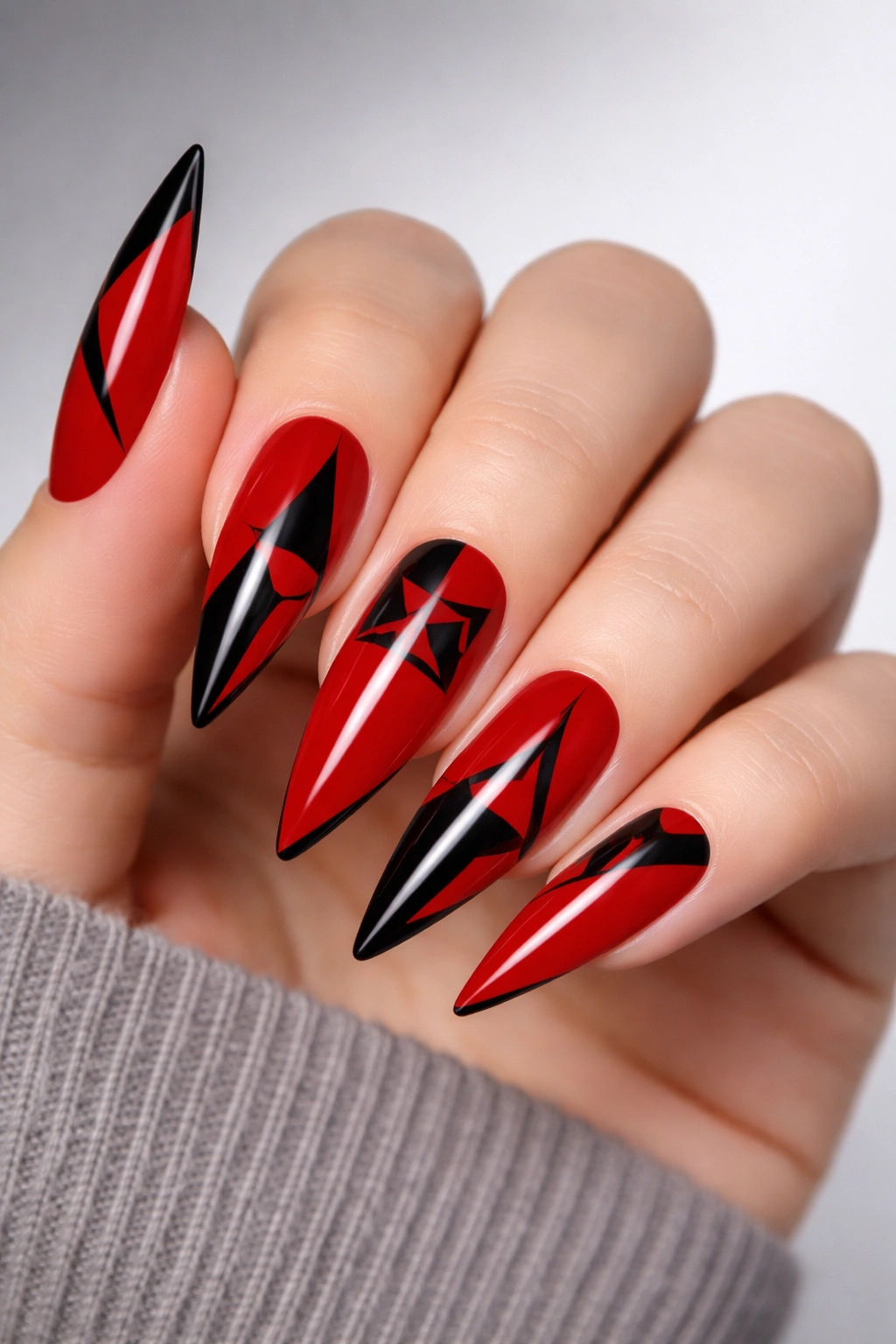 Close-up of red nails with black geometric shapes on stiletto nails