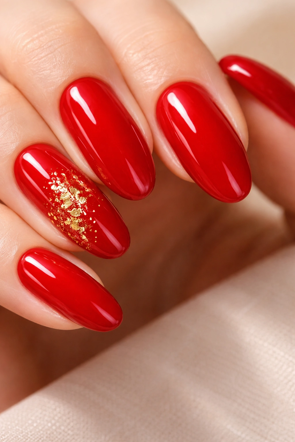 Close-up of long red round nails with gold foil detailing