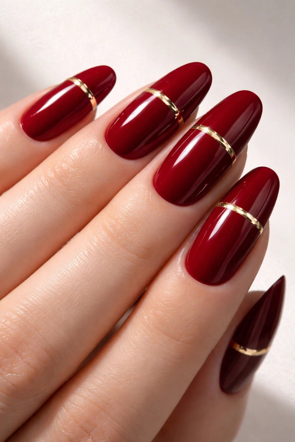 Long red nails with thin gold foil strip accent