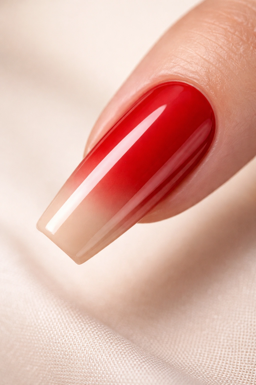 Close-up of coffin nail with red base and nude tip gradient