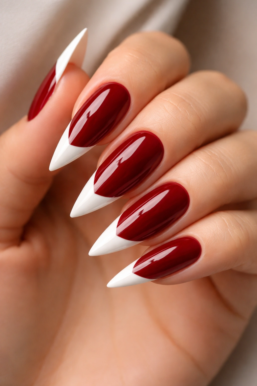 Deep red nails with glossy white French tips on stiletto nails