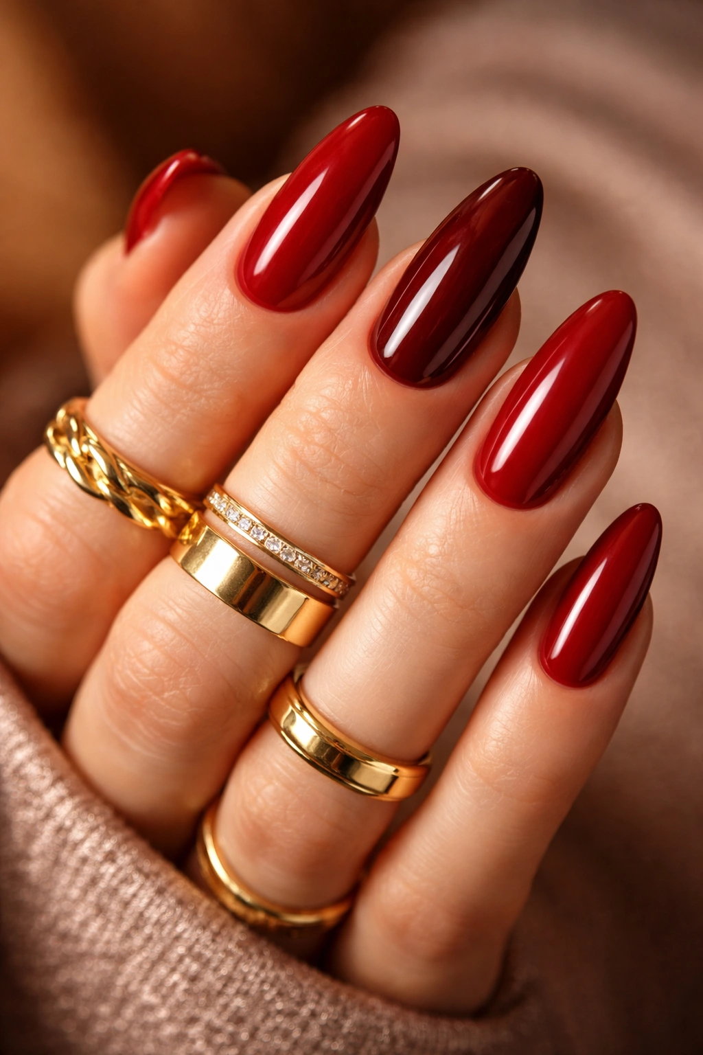Close-up of nails in brick red and burgundy hues against a neutral backdrop