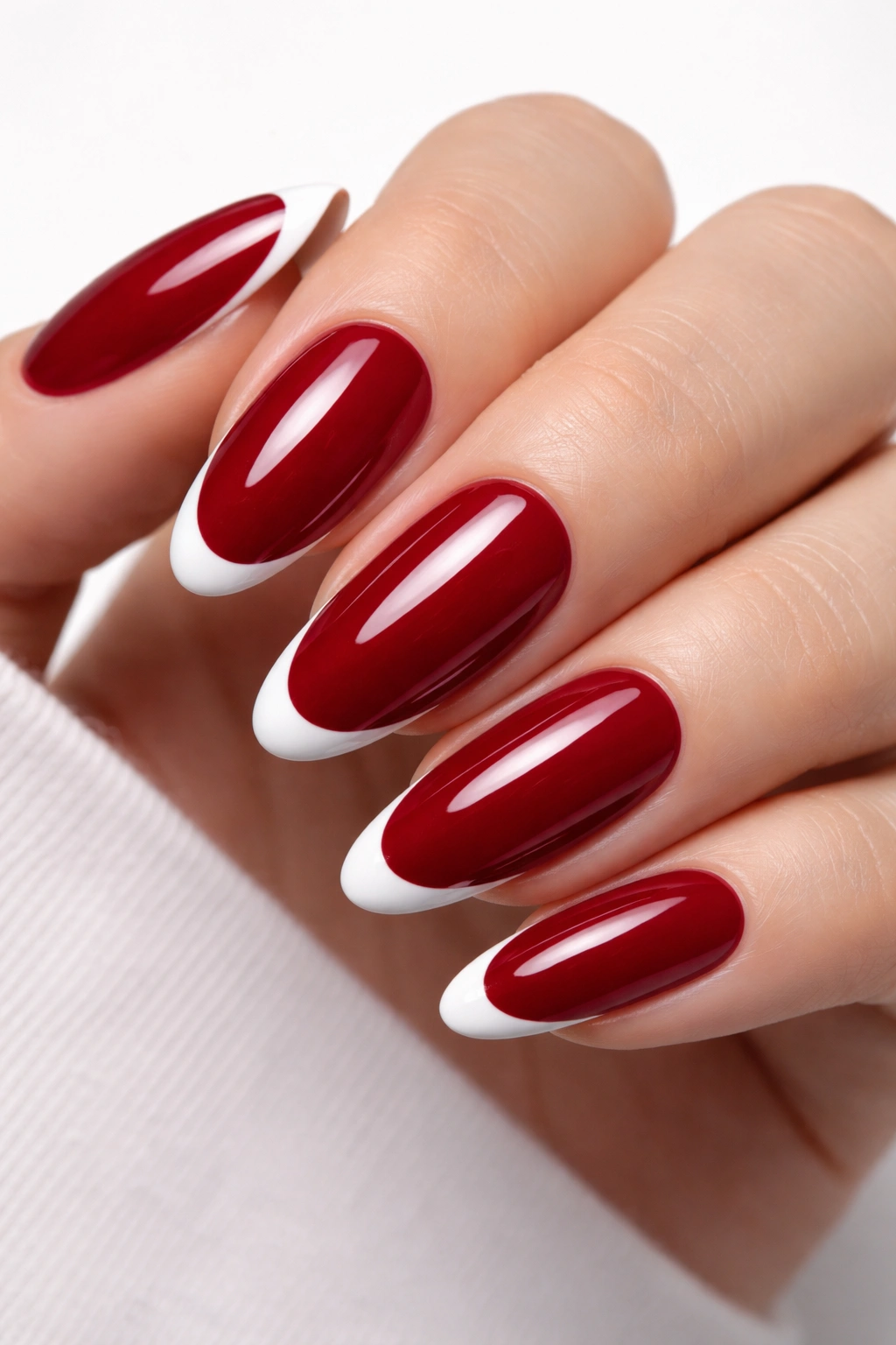 Close-up of red oval nail with minimalist white French tip