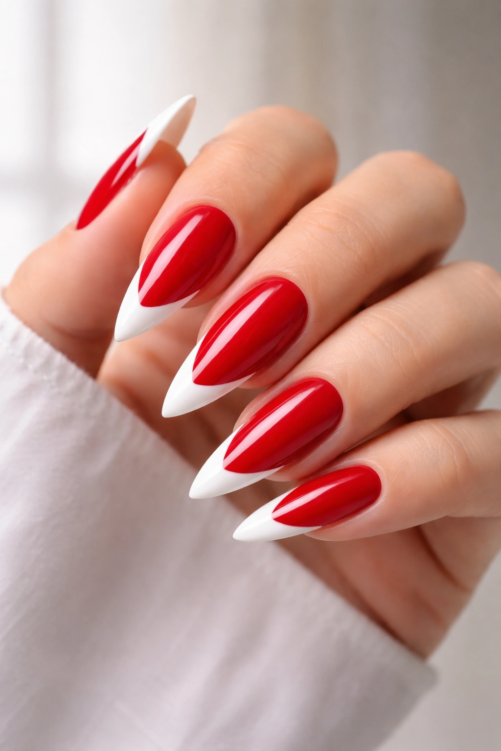 Close-up of red stiletto nails with white French tips on medium length.