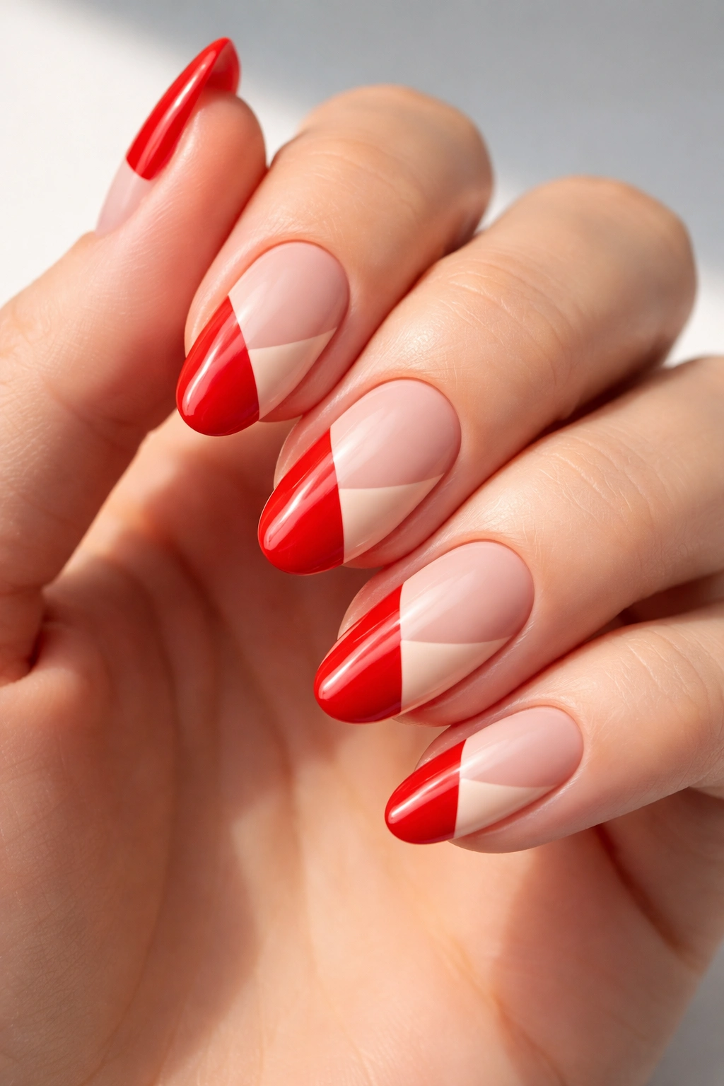 Close-up of nails with red and nude color-block geometric design.