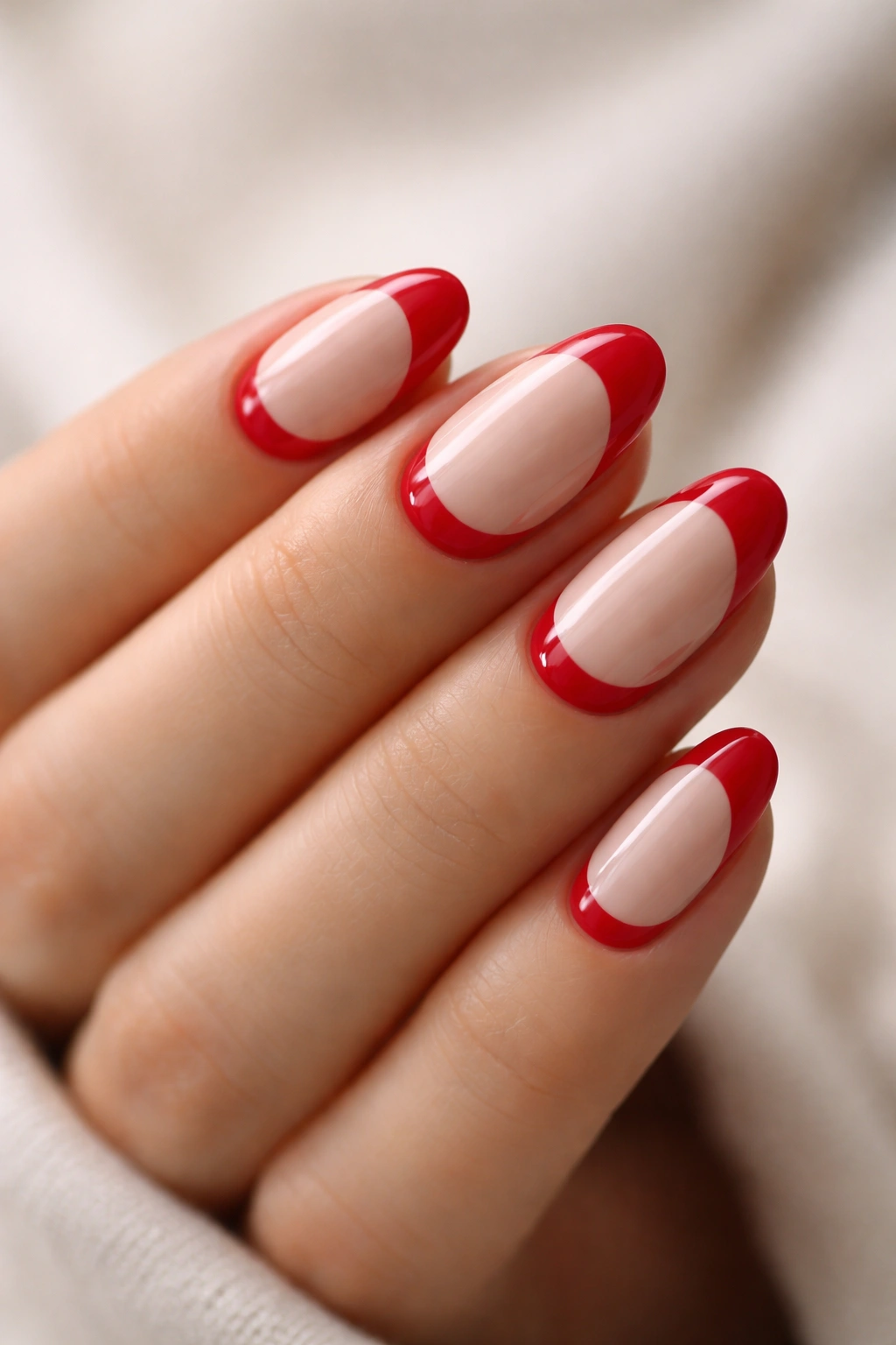 Close-up of red and nude half-moon nails on short almond nails.