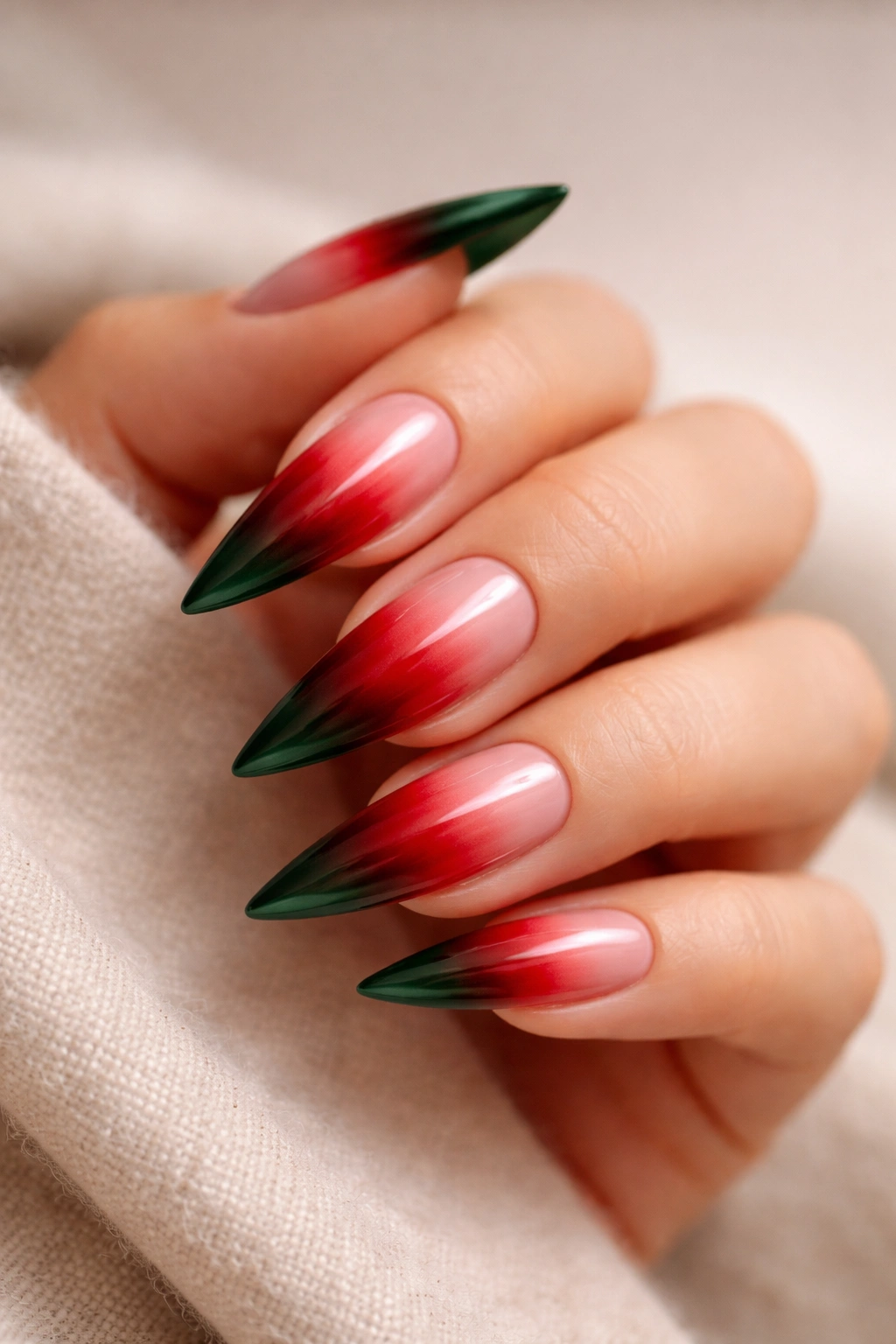 Stiletto nail with red ombre fading to green tip on nude base