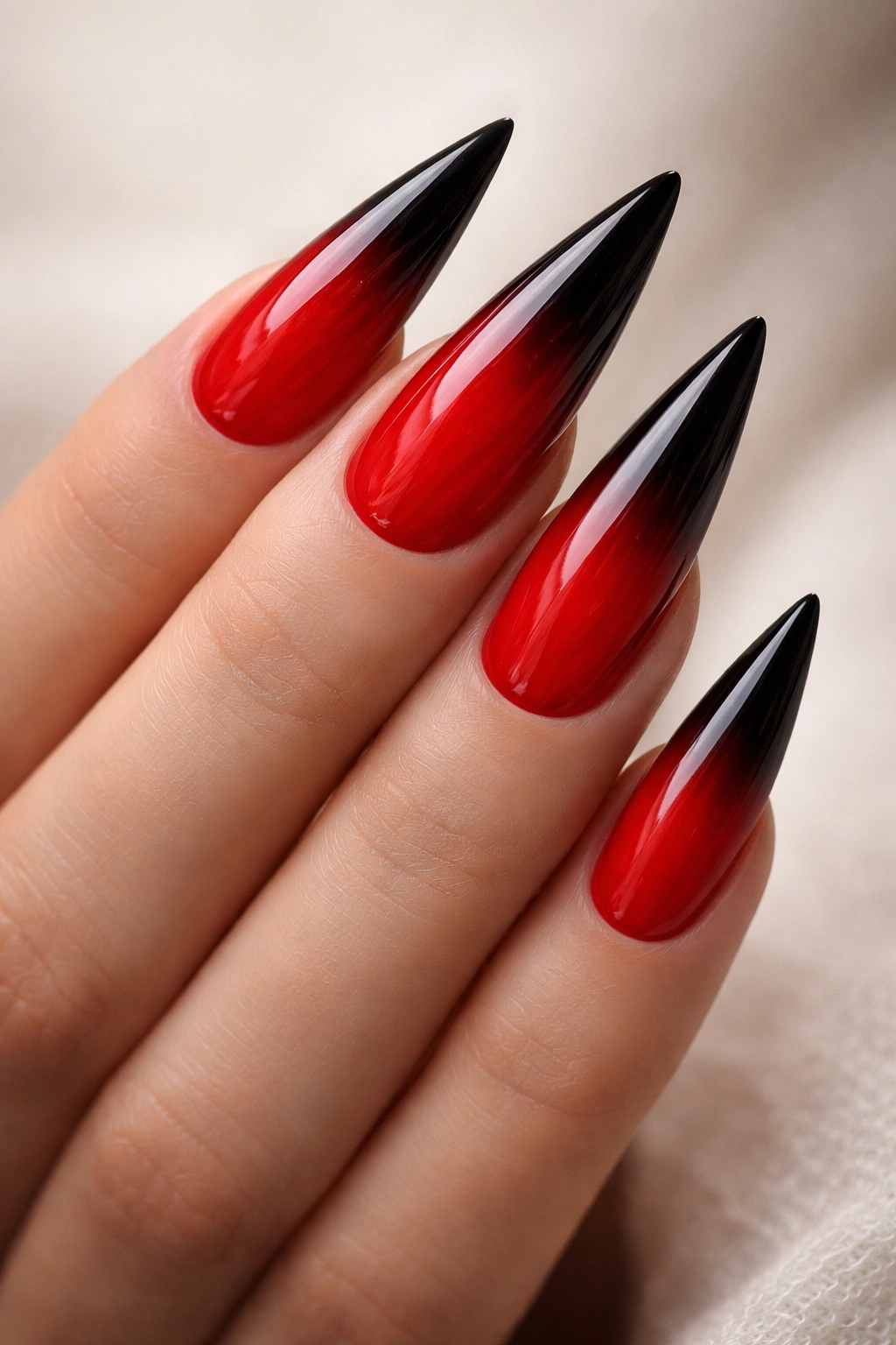 Red to black ombré stiletto nails on a hand