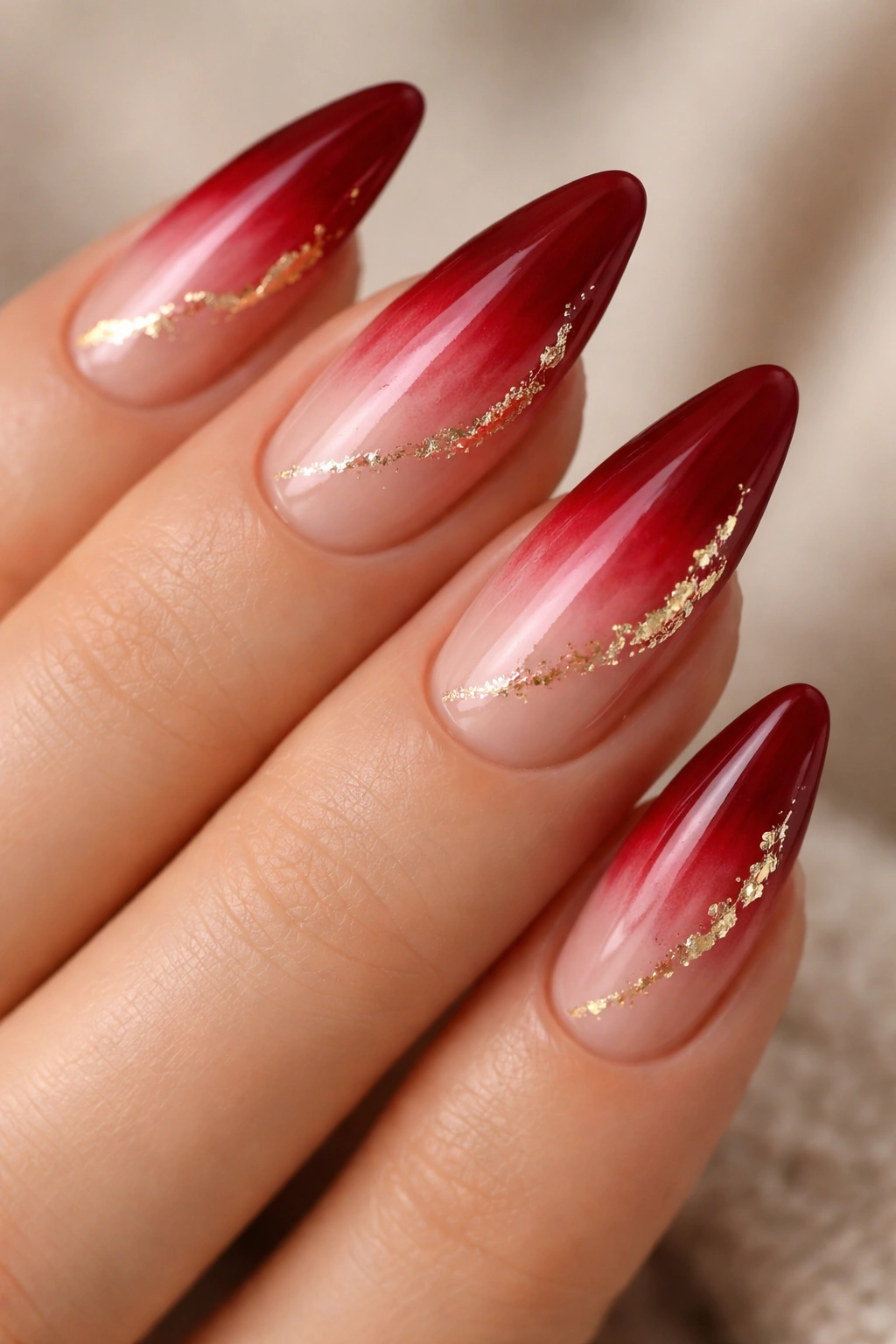 Almond nails with red ombre and delicate gold foil accents